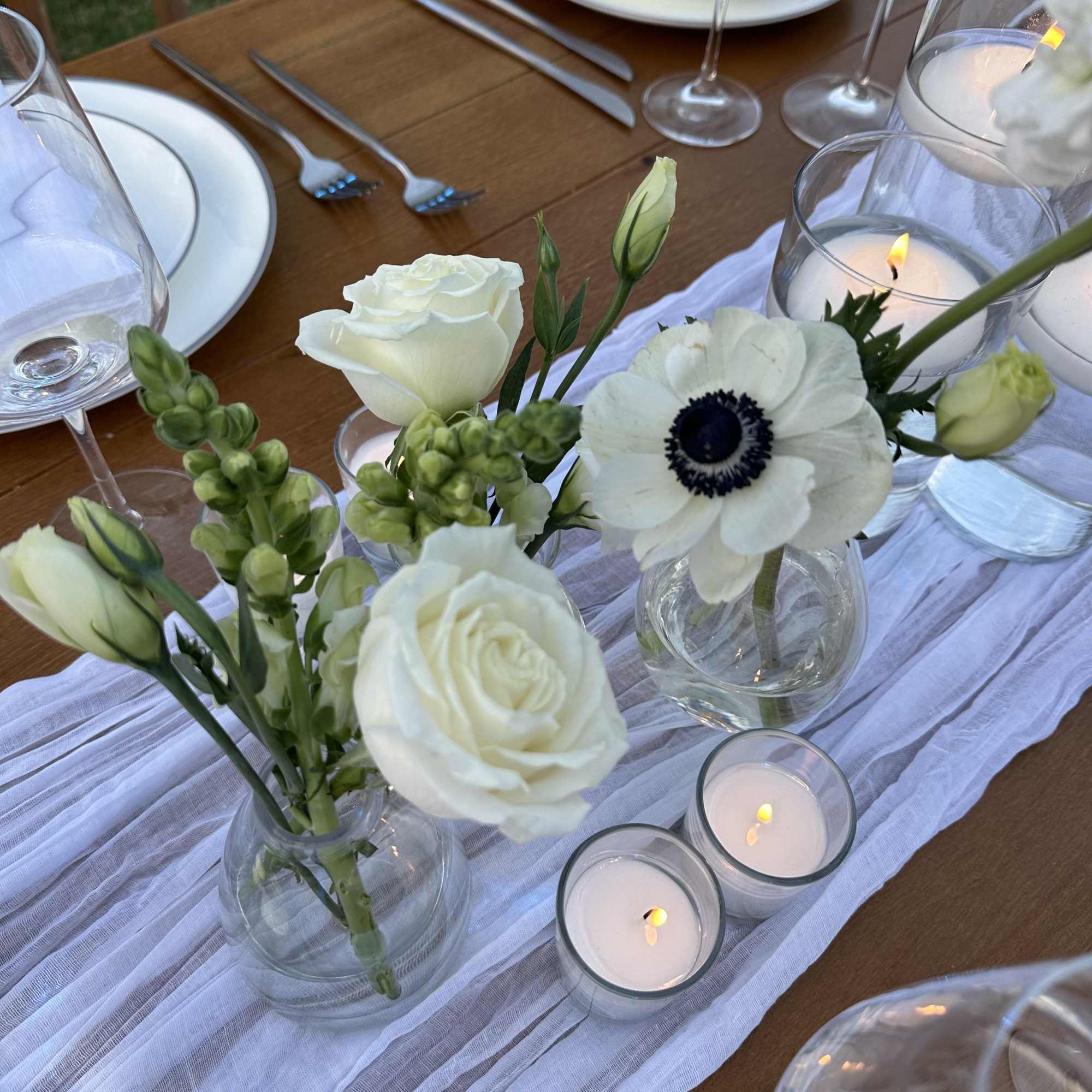 White floral centerpieces with candles on a set dining table