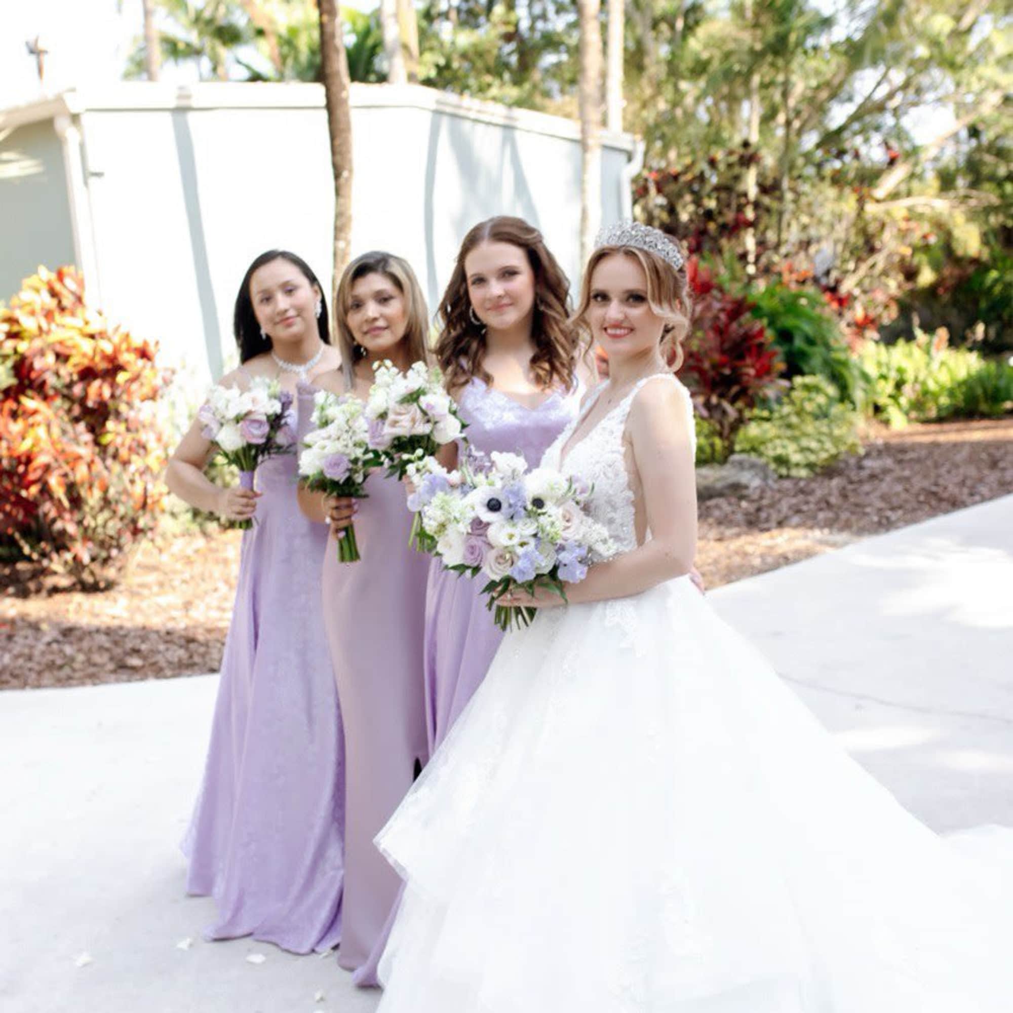 Bride and bridesmaids holding lavender and white bouquets outdoors