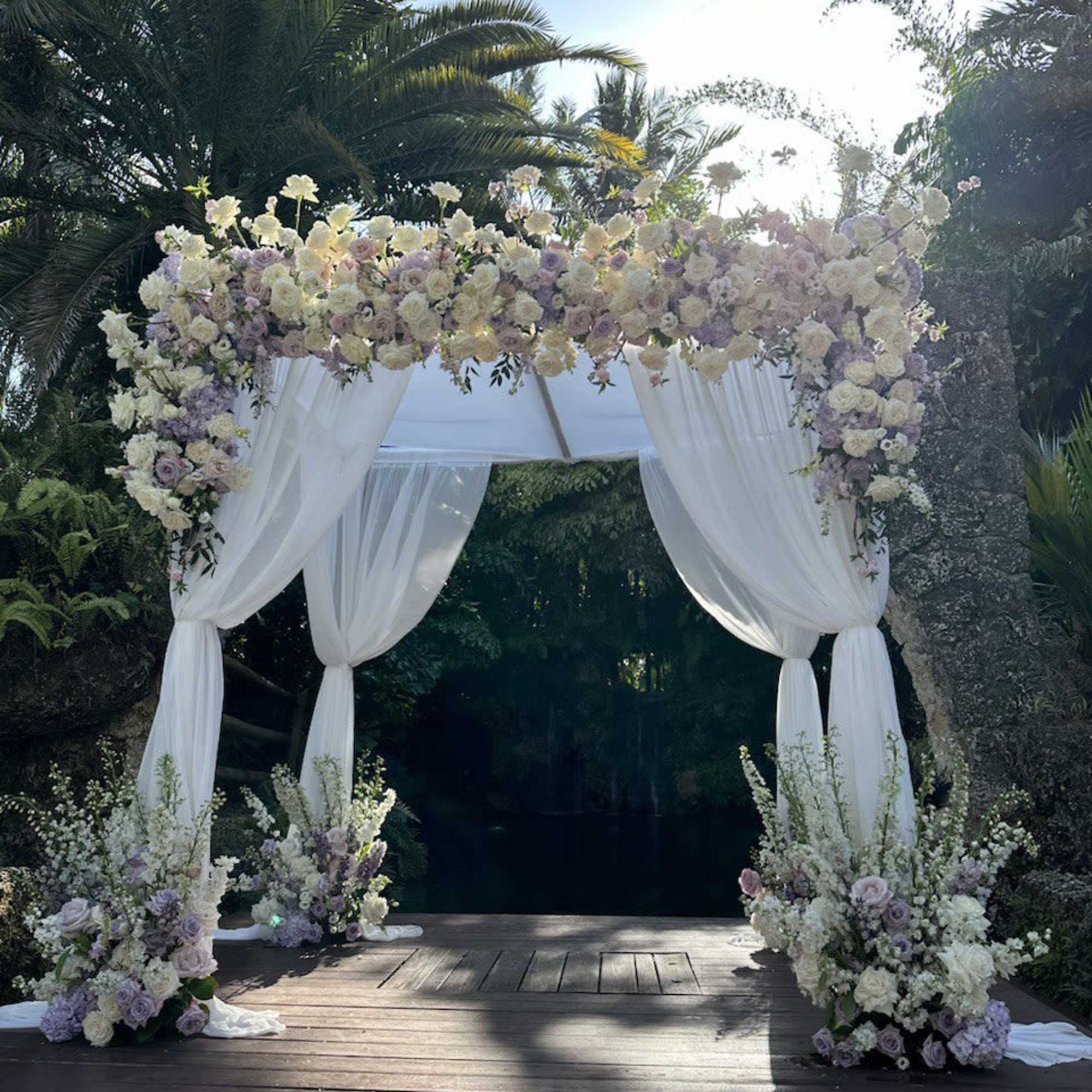 Floral wedding arch with white drapes and pastel blooms