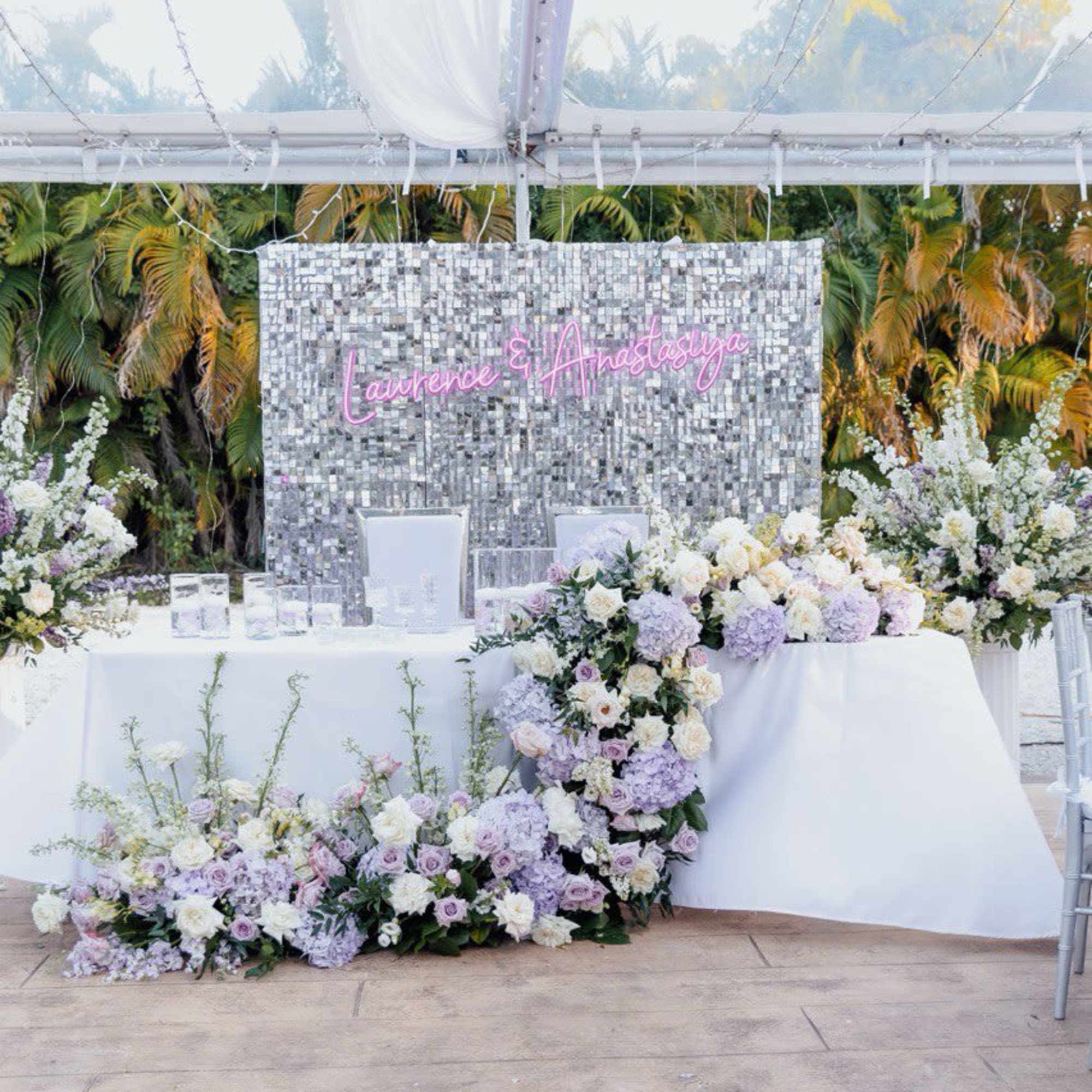 Lavender and white floral wedding backdrop with a sequin wall and table