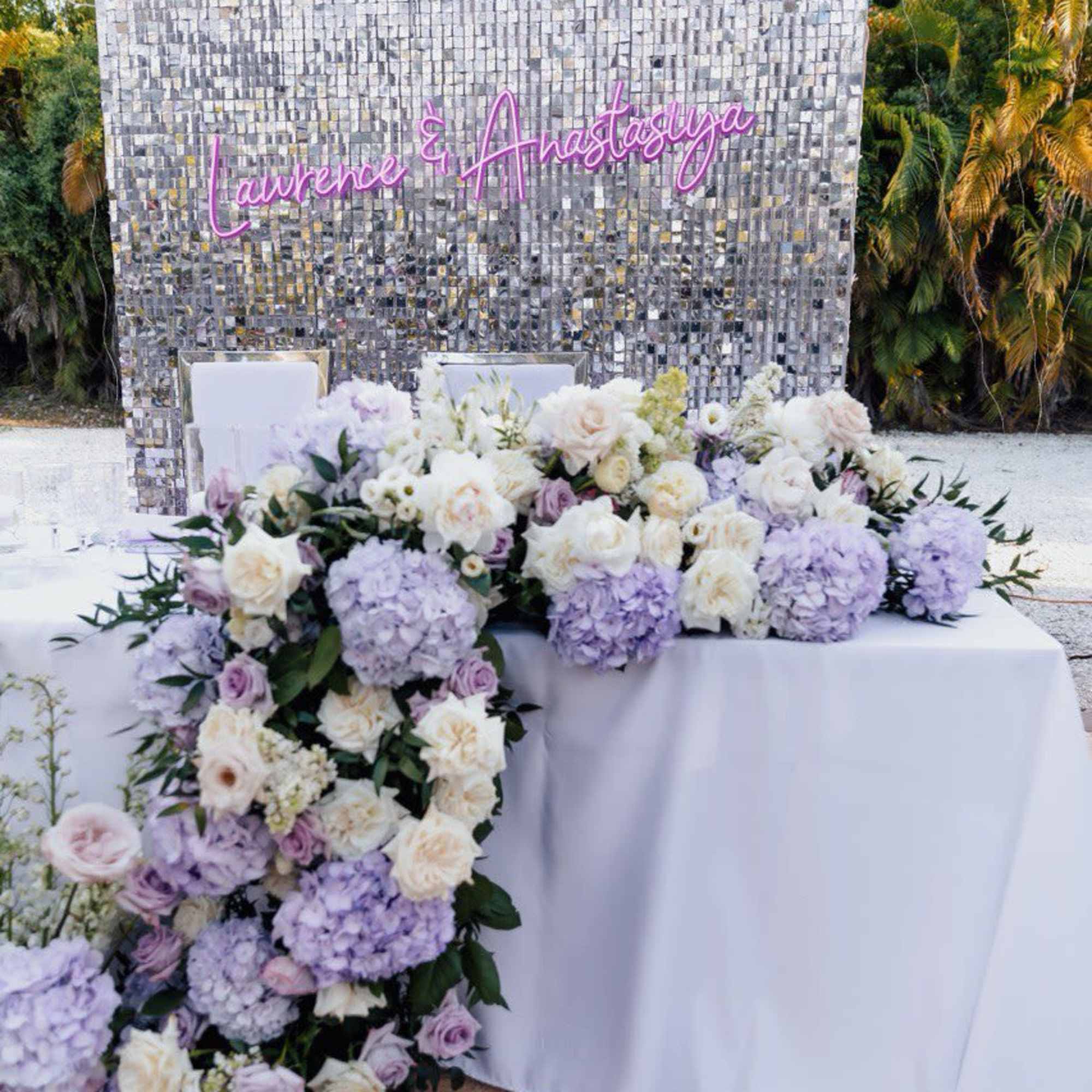 Lavender and white floral arrangement with roses and hydrangeas on a draped table