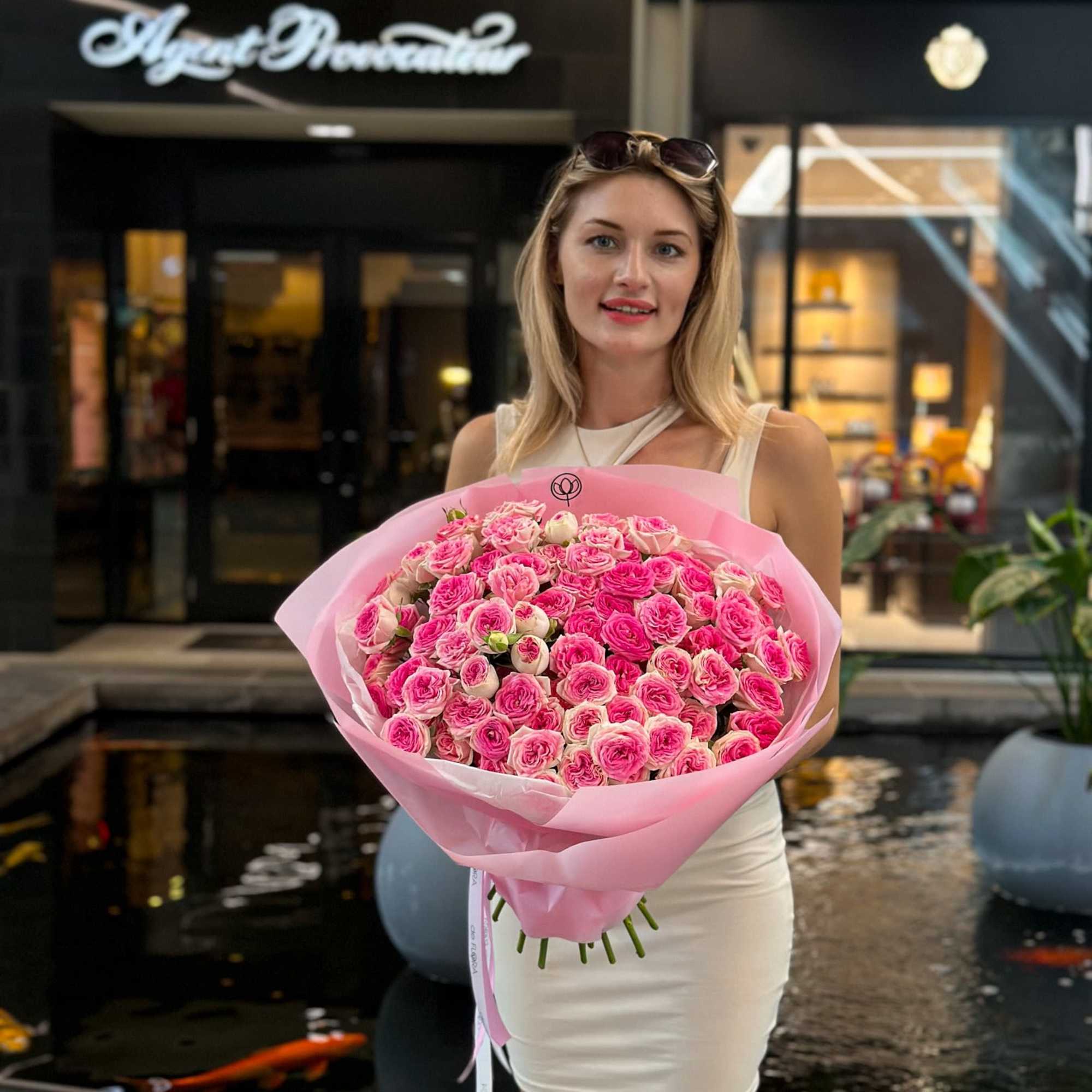 Woman holding a large bouquet of pink roses wrapped in pink paper