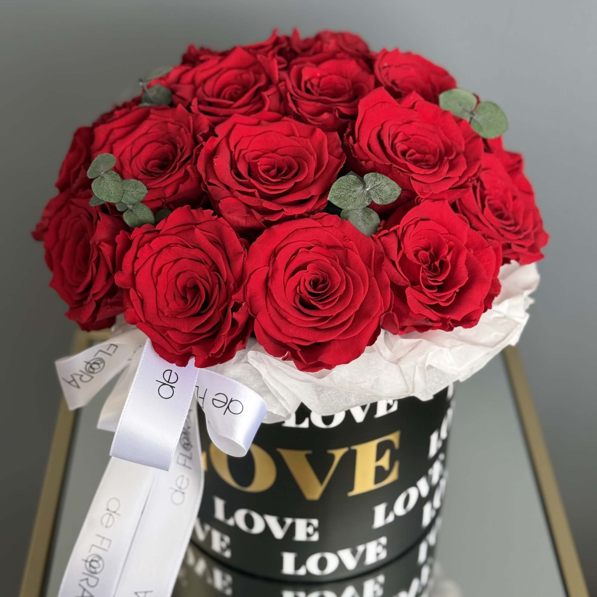 Bouquet of red roses in a black box with white ribbon