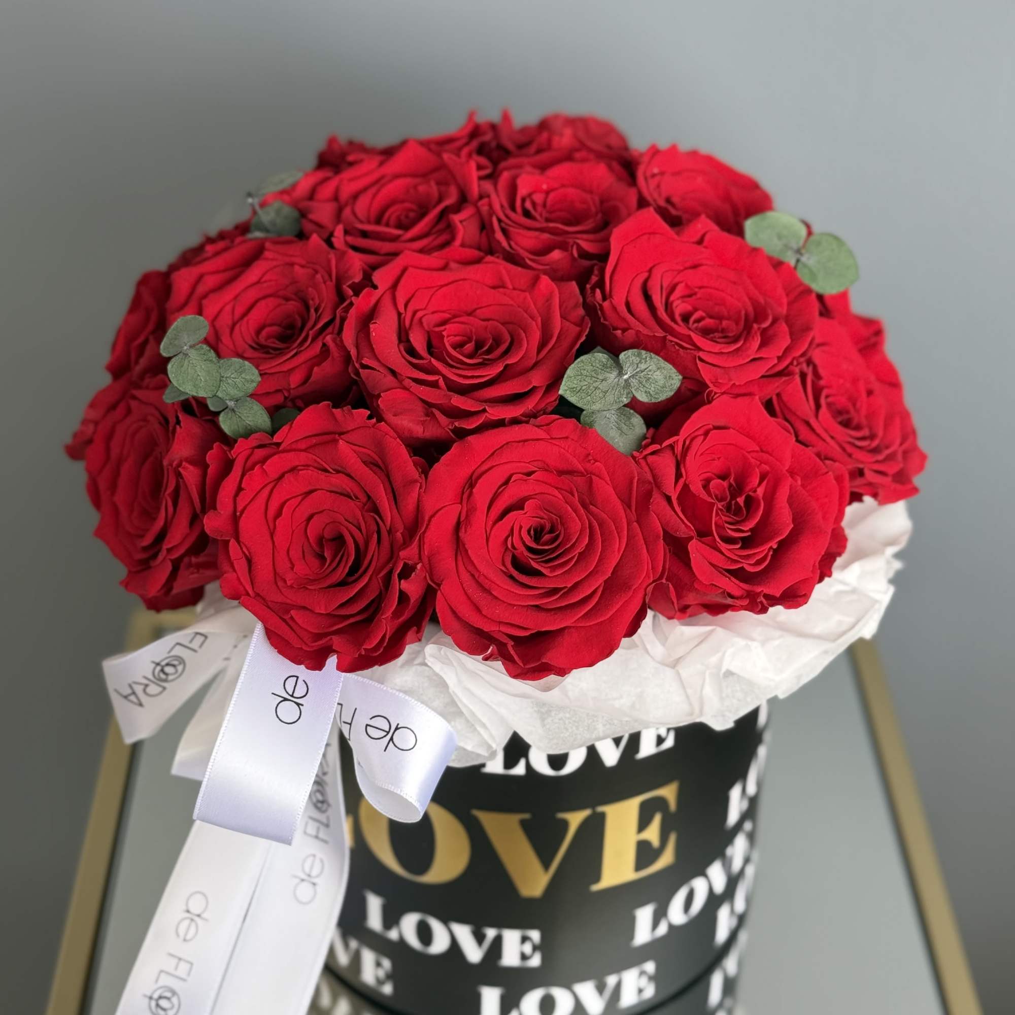 Red roses arranged in a black hat box with a white ribbon