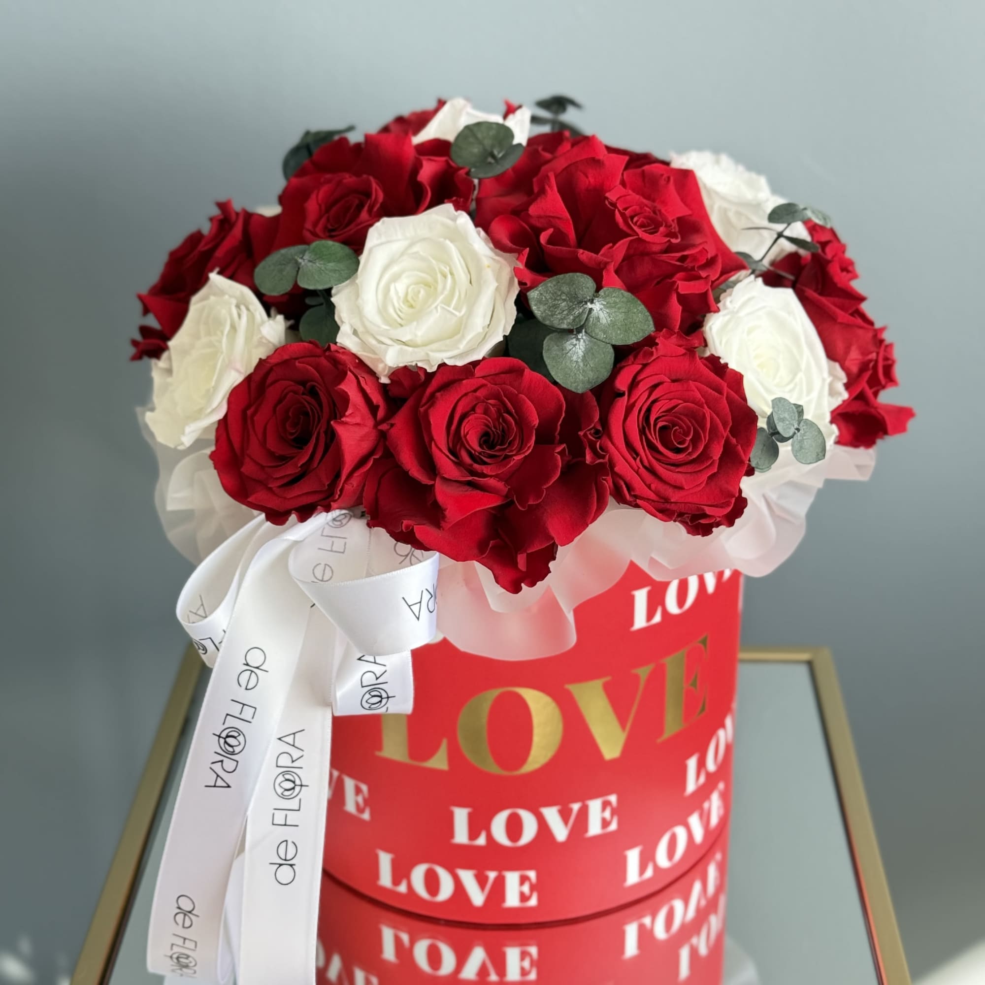 Red and white roses in a round gift box with a ribbon