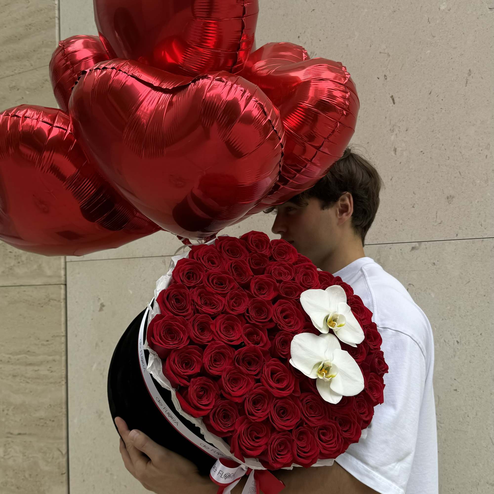 Heart-shaped red balloon bouquet with a round red rose arrangement and white orchids