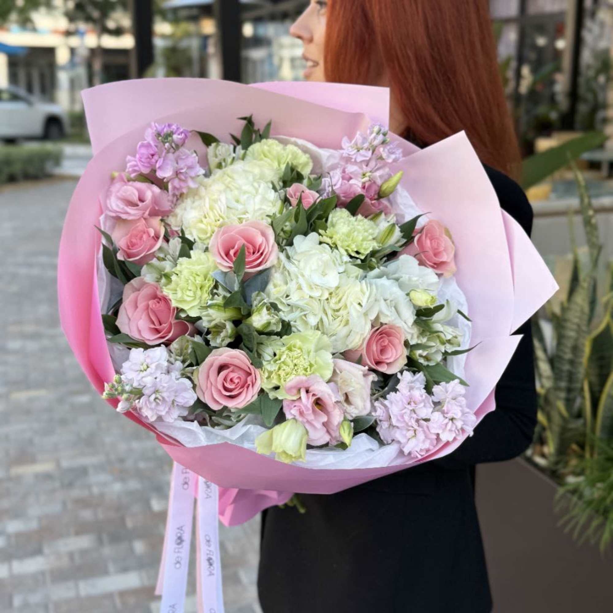 Large pink and white bouquet of roses, carnations, and hydrangeas wrapped in pink paper