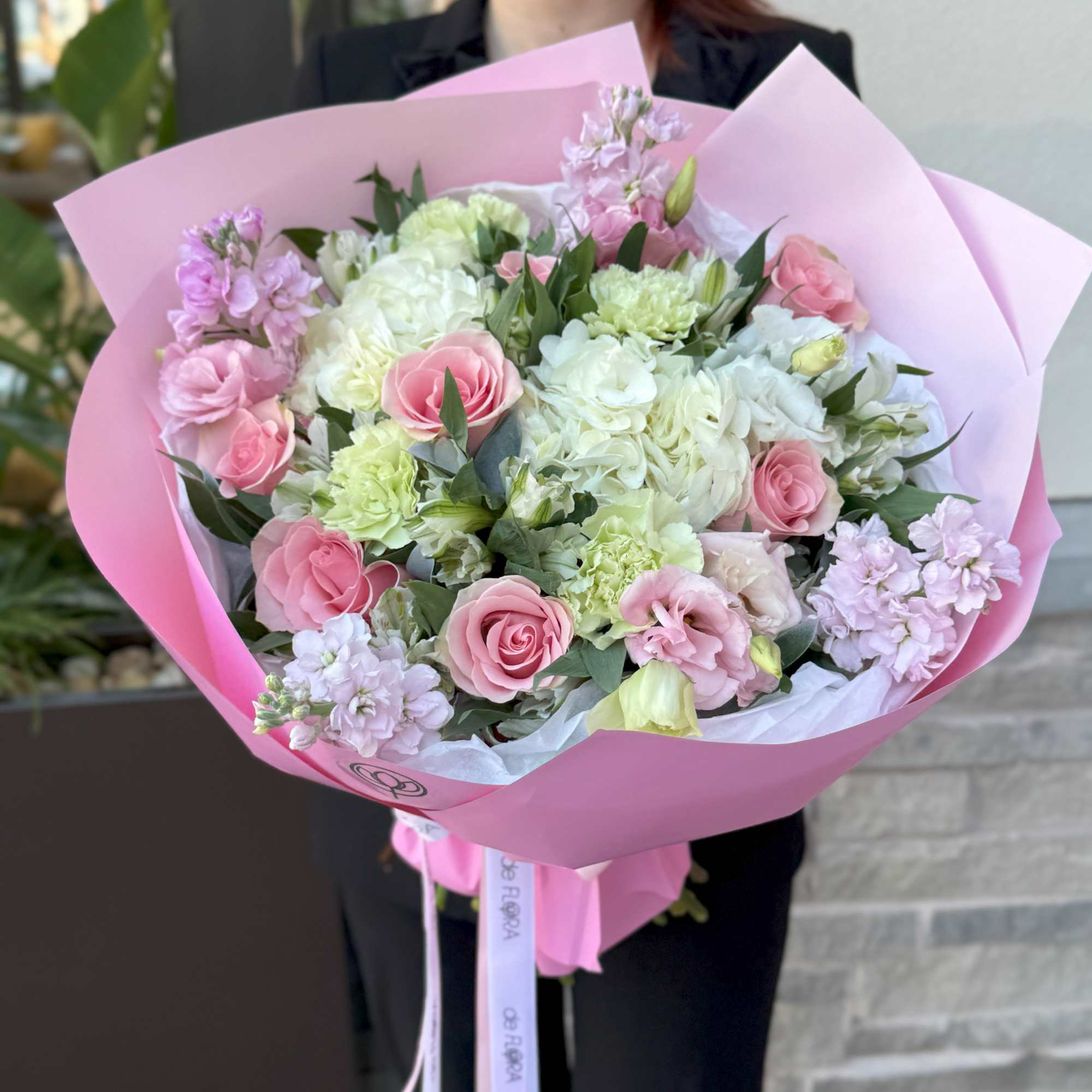 Pink and white bouquet with roses and carnations wrapped in pink paper