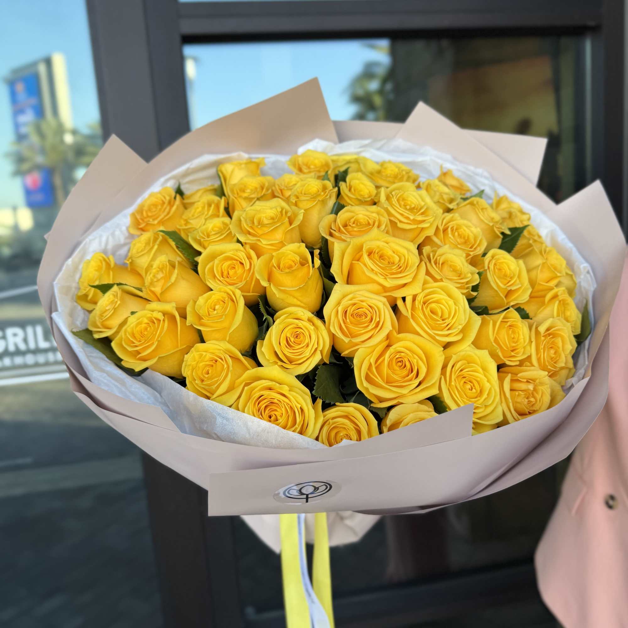 Bouquet of yellow roses wrapped in pale paper