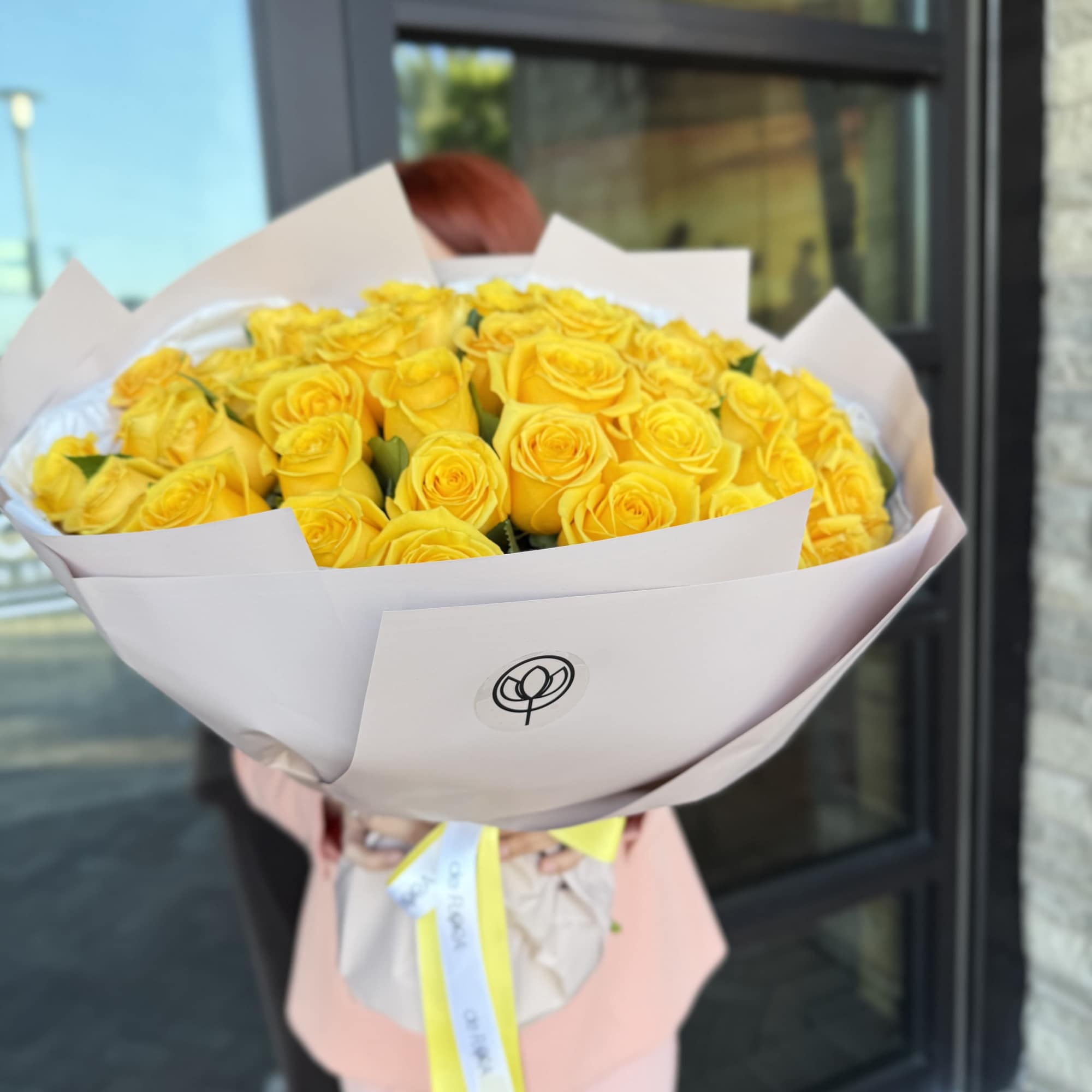 Large bouquet of yellow roses wrapped in pale paper