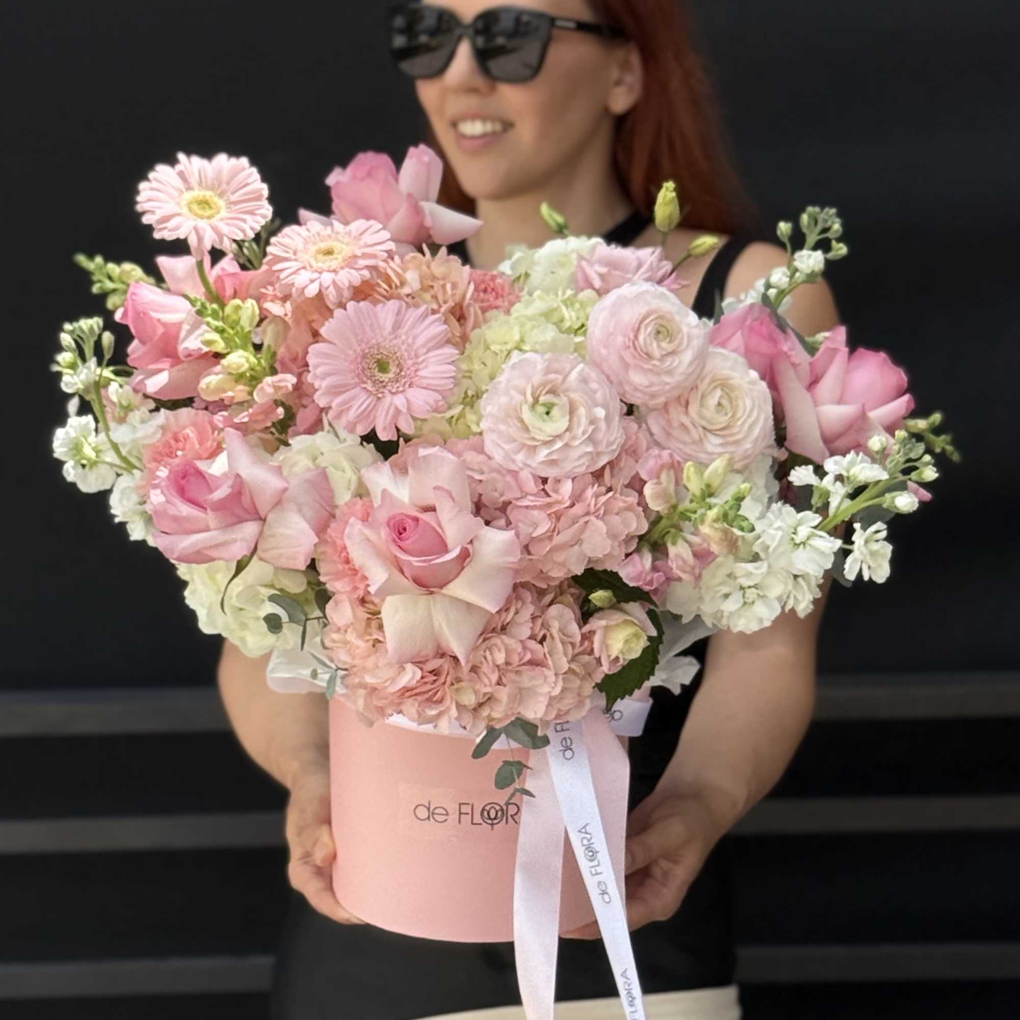 Large pastel pink and white flower arrangement with roses and gerberas in a round pink hatbox.