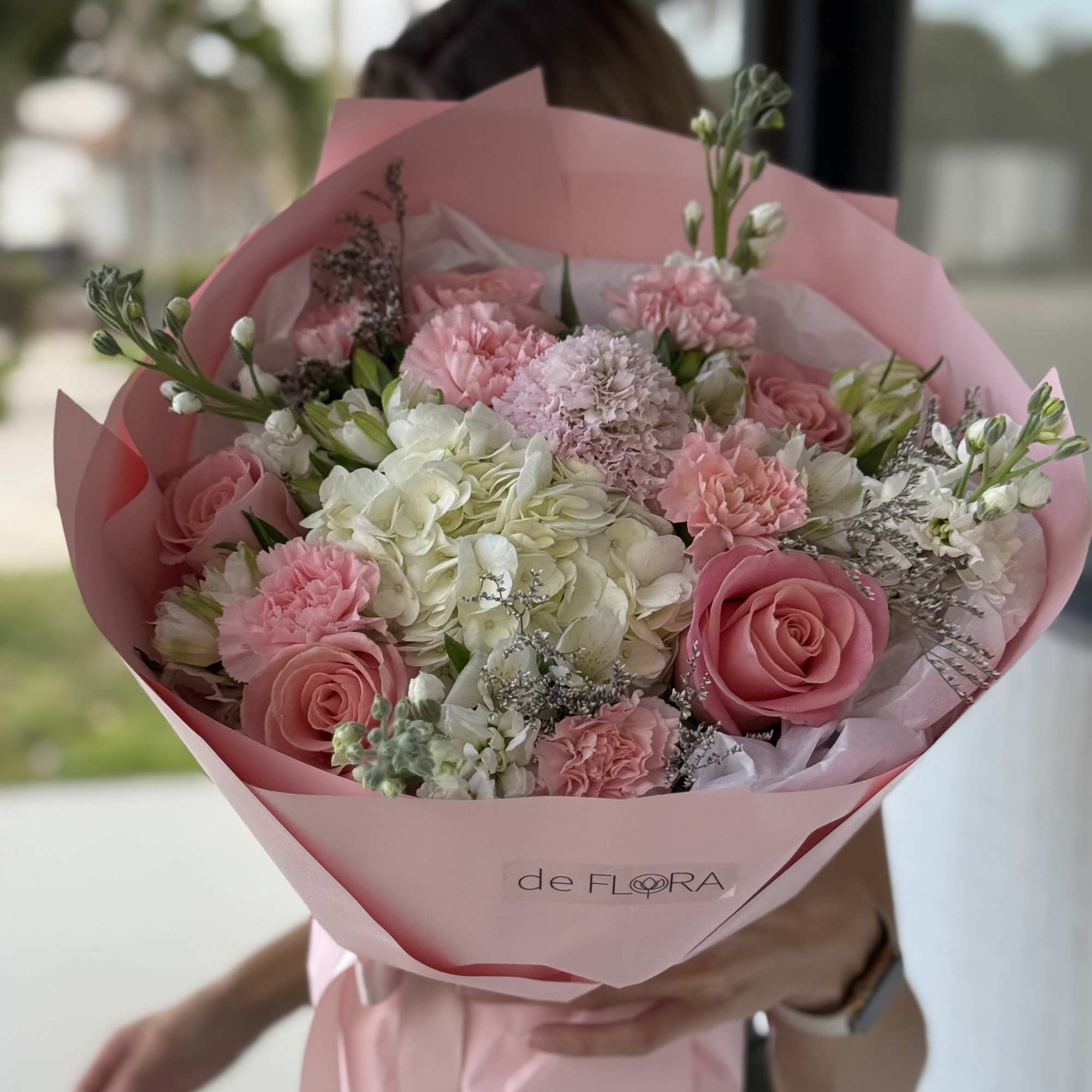 Pink bouquet with roses, carnations, and white hydrangea in pink wrap