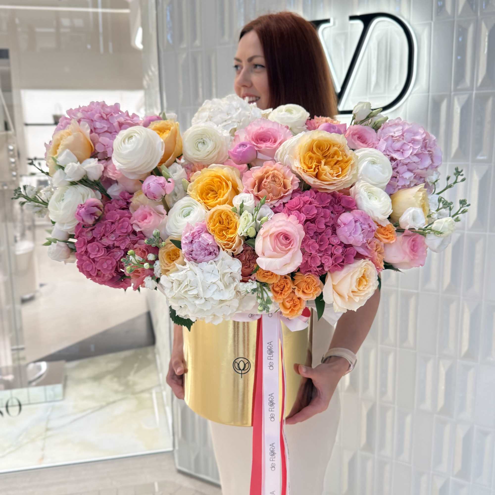 Large mixed bouquet of pink, white, and peach flowers in a gold box