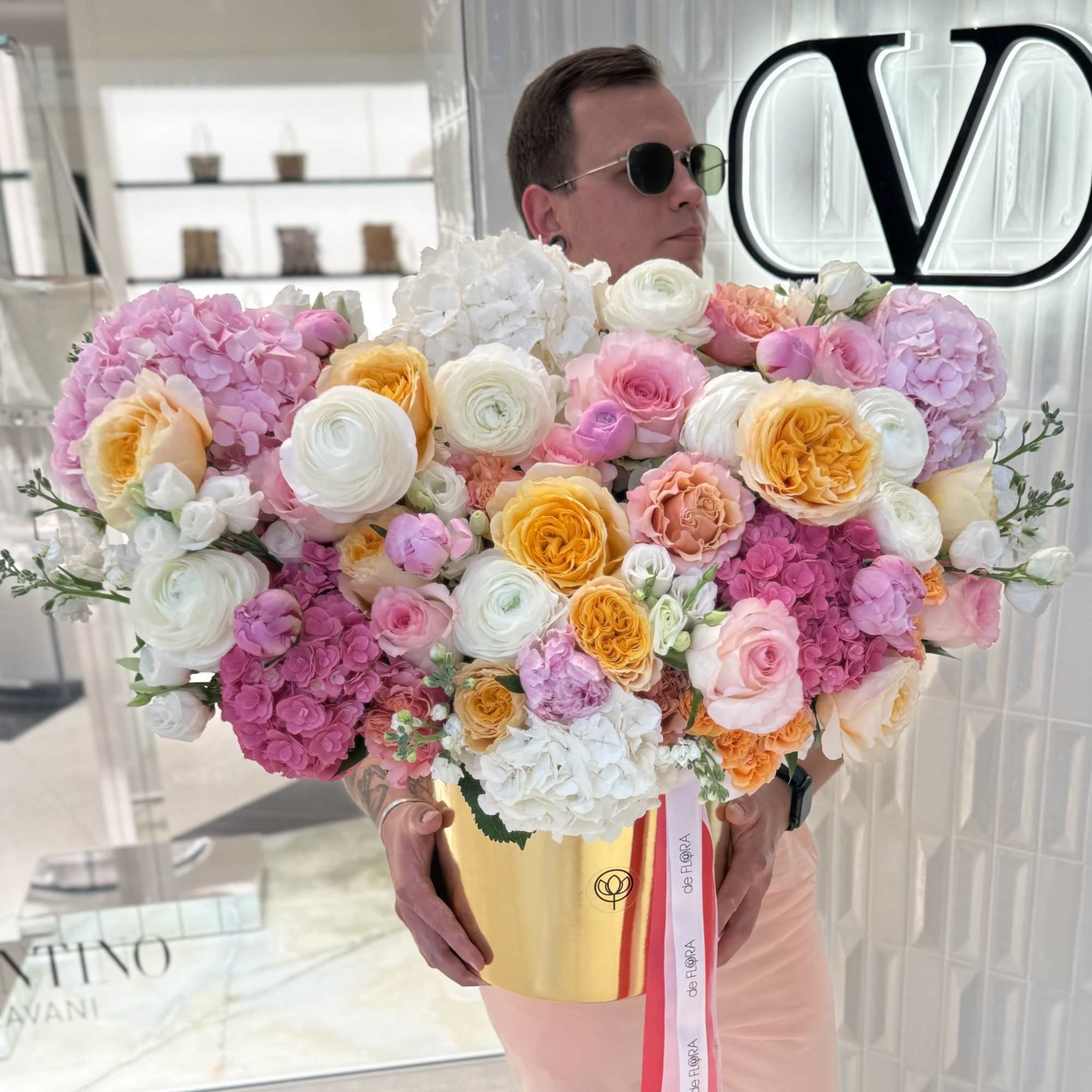 Large bouquet of pink, white, and yellow flowers in a gold box