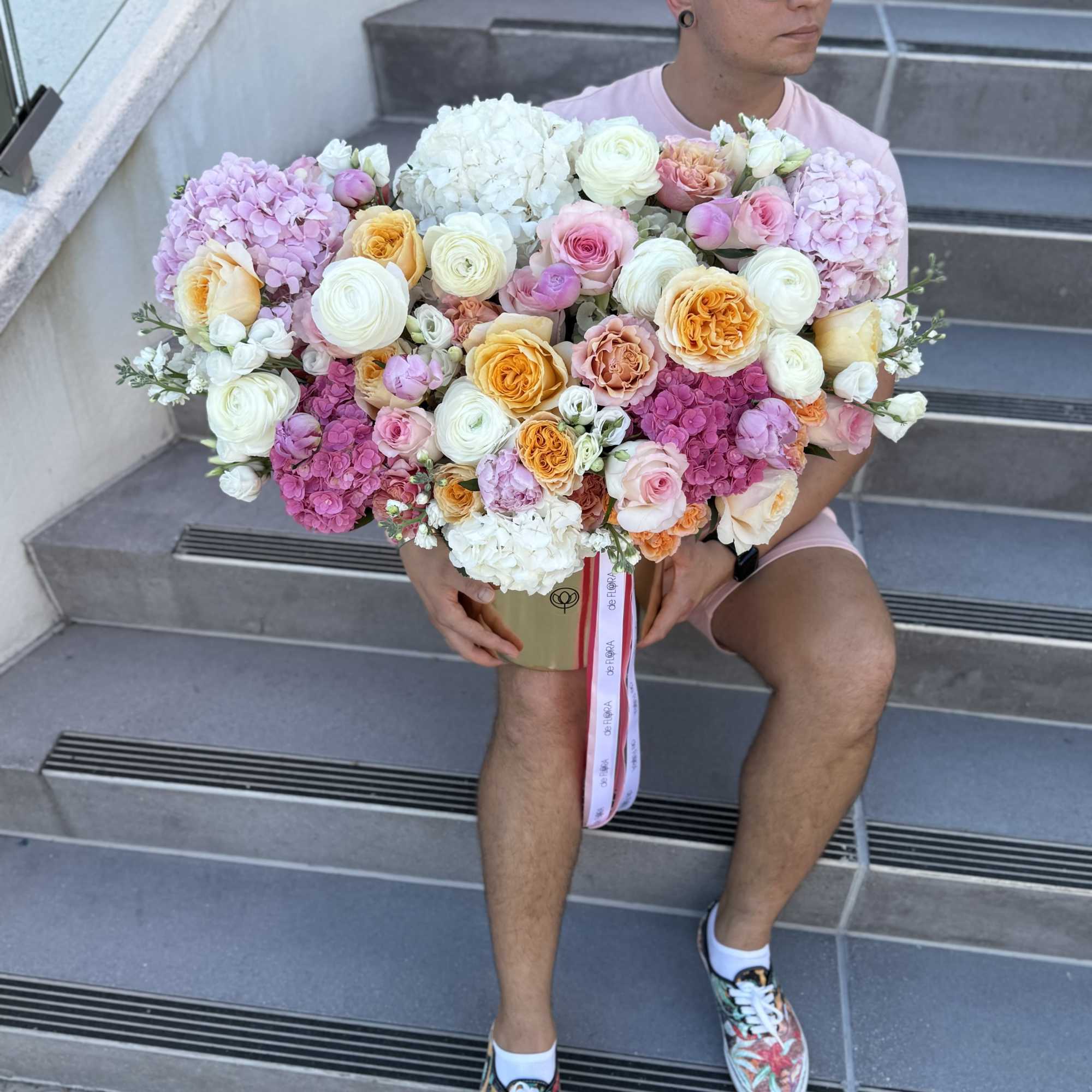 Large pastel bouquet of pink, white, and peach flowers in a gold box