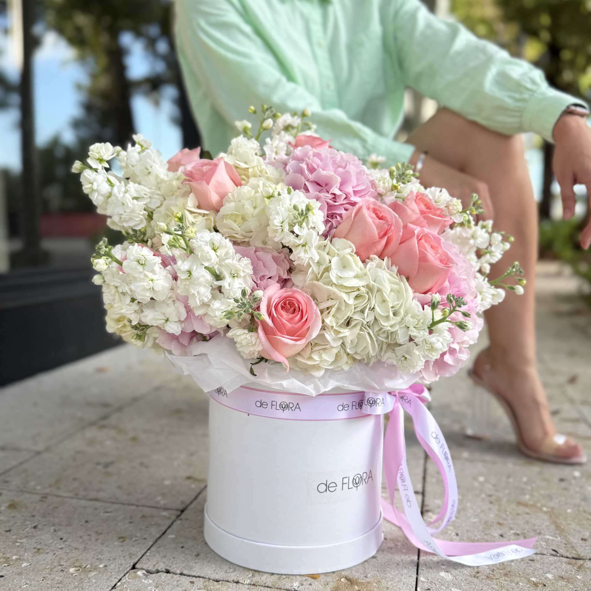 Pink and white flower arrangement in a white hat box with ribbon