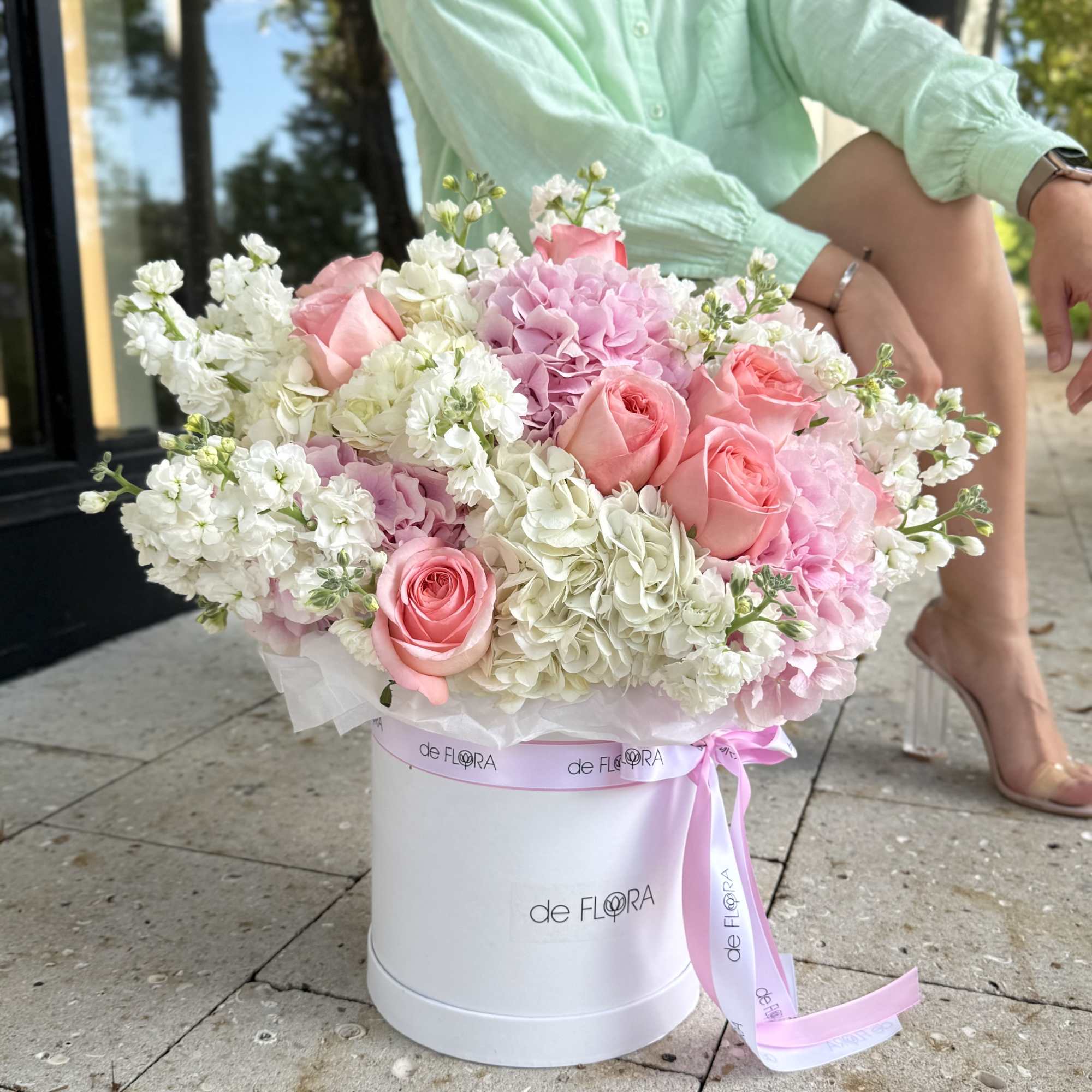 Pink roses and hydrangeas in a white hatbox with a ribbon