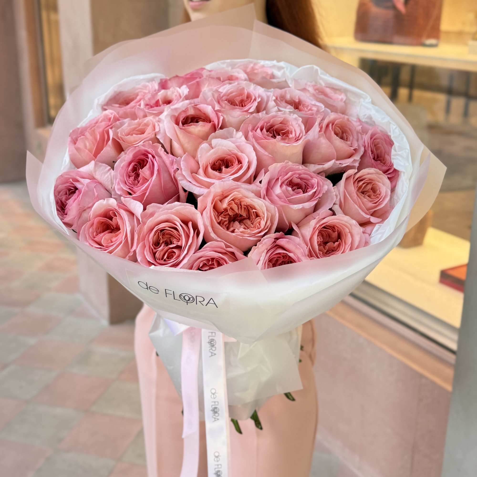 Large bouquet of pink roses wrapped in white paper with a ribbon
