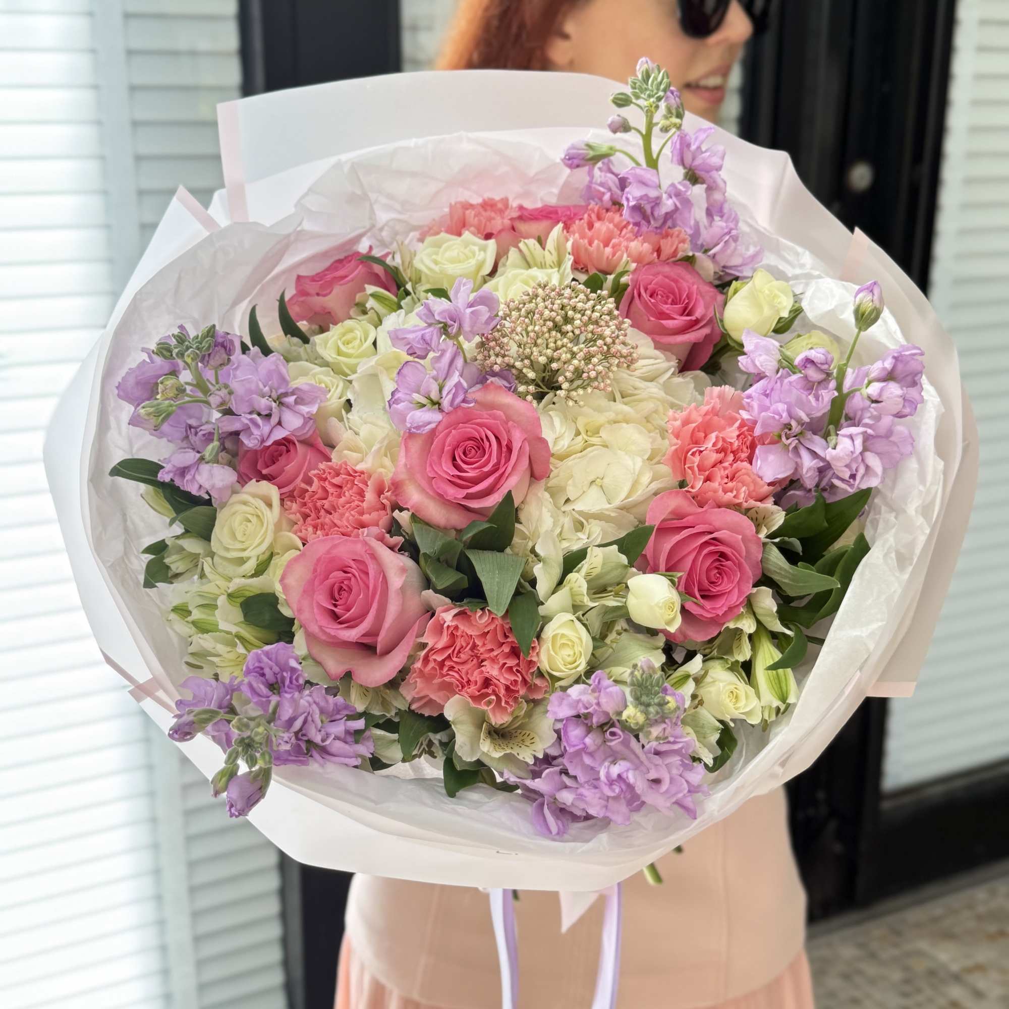 Large bouquet of pink and cream roses with lavender flowers wrapped in white paper