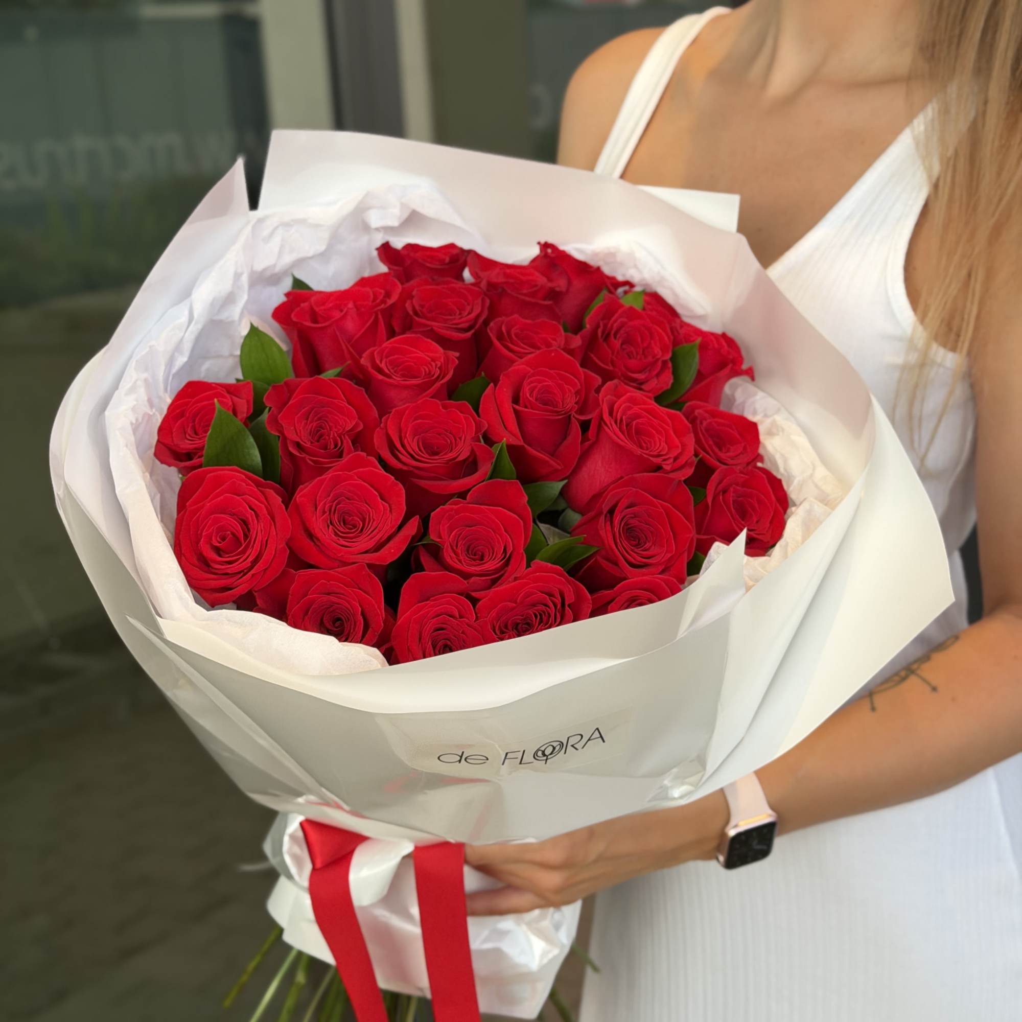Bouquet of red roses wrapped in white paper with a red ribbon