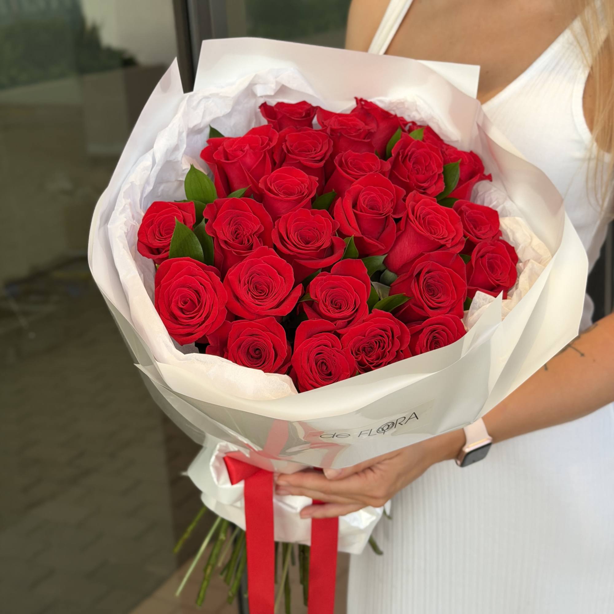 Bouquet of red roses wrapped in white paper with a red ribbon
