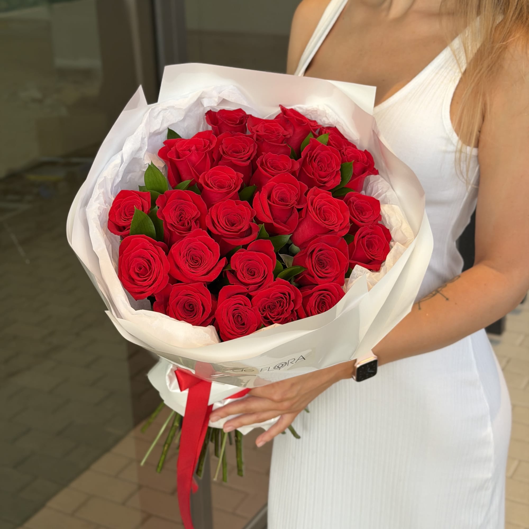 Woman holding a large bouquet of red roses wrapped in white paper