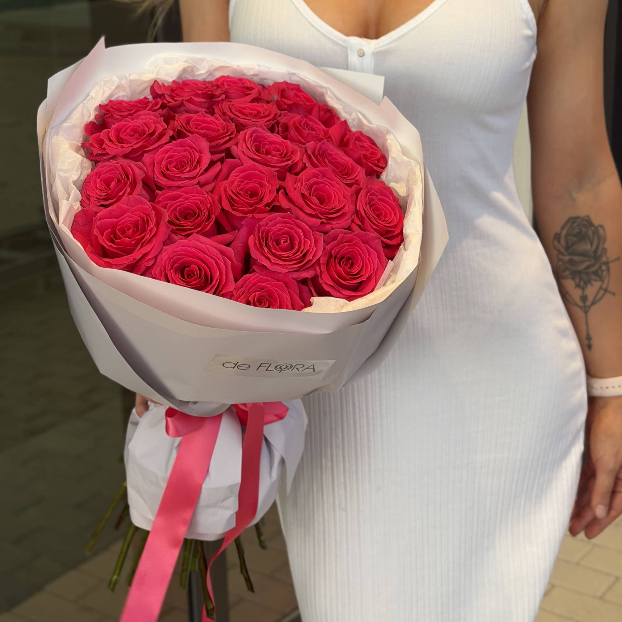 Bouquet of bright pink roses wrapped in pale paper with a ribbon