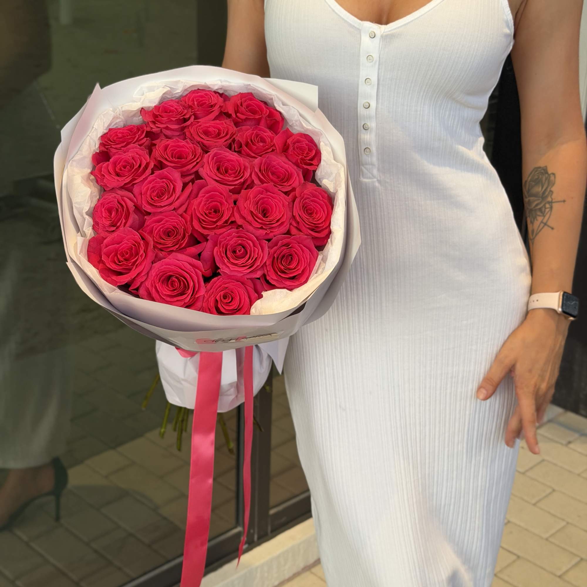 Bouquet of bright pink roses wrapped in white paper with a pink ribbon