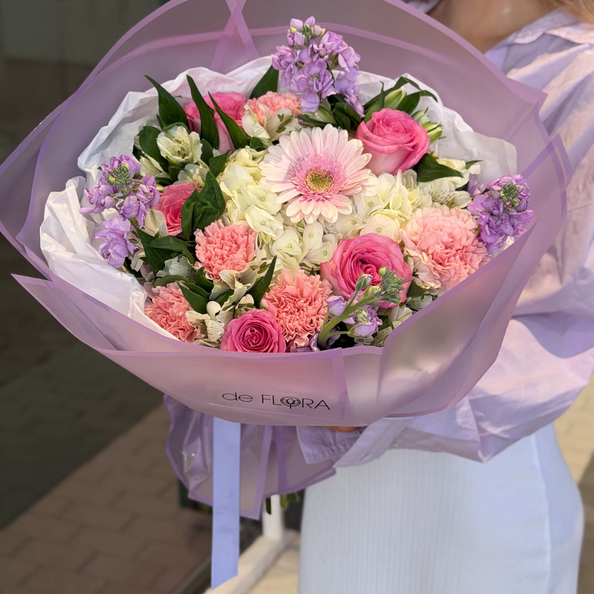 Bouquet of pink and white flowers wrapped in lavender paper