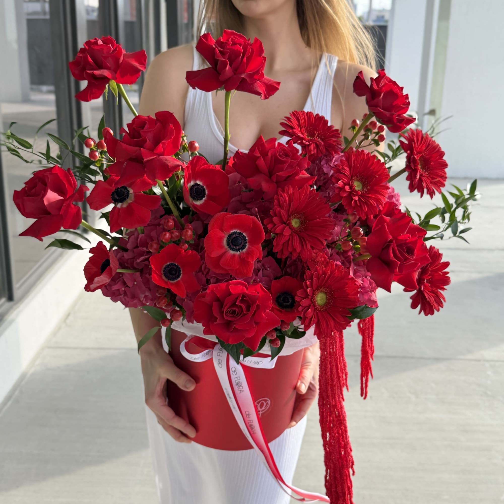 Woman holding a large red bouquet in a round box