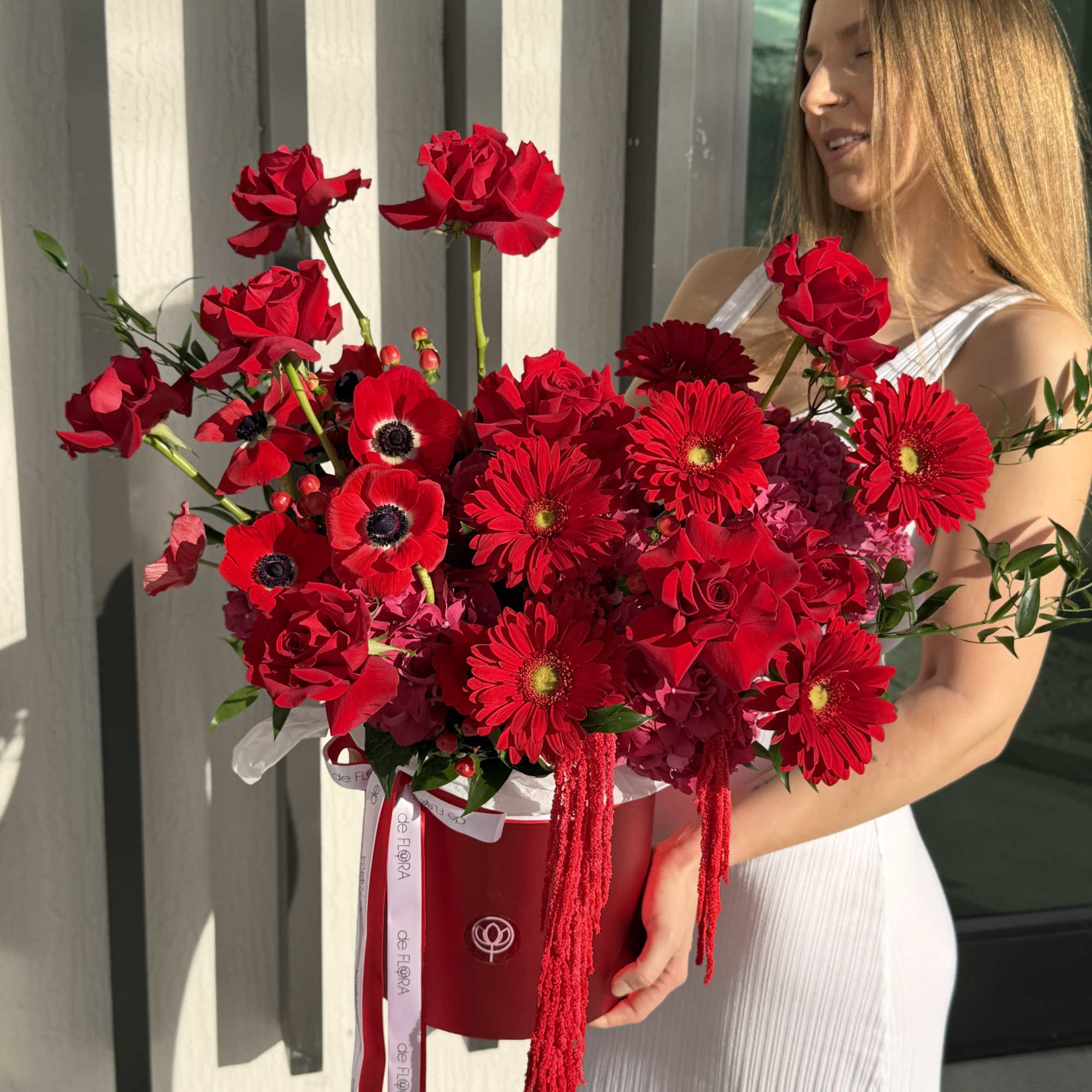 Woman holding a large red flower arrangement in a box