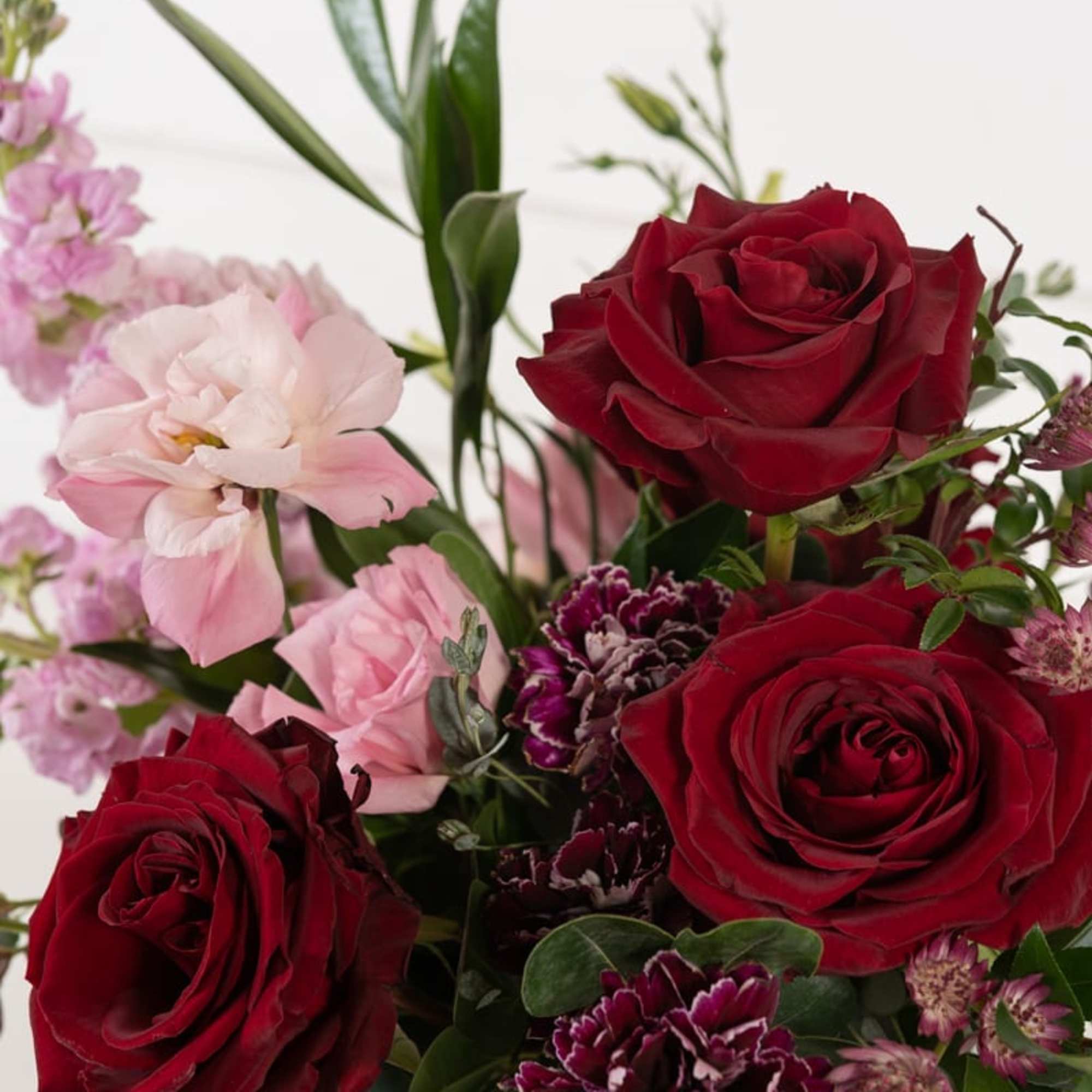 Bouquet of red roses and pink flowers with greenery