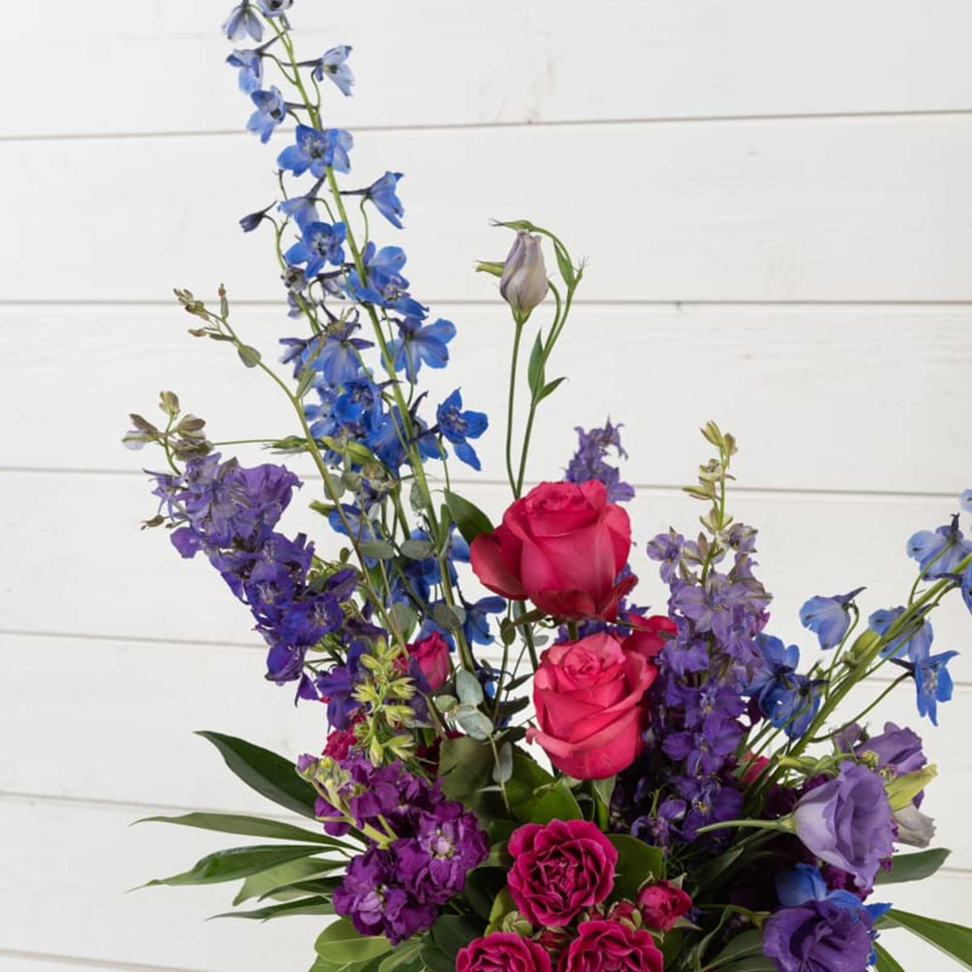 Mixed bouquet of pink roses and blue-purple flowers in a glass vase