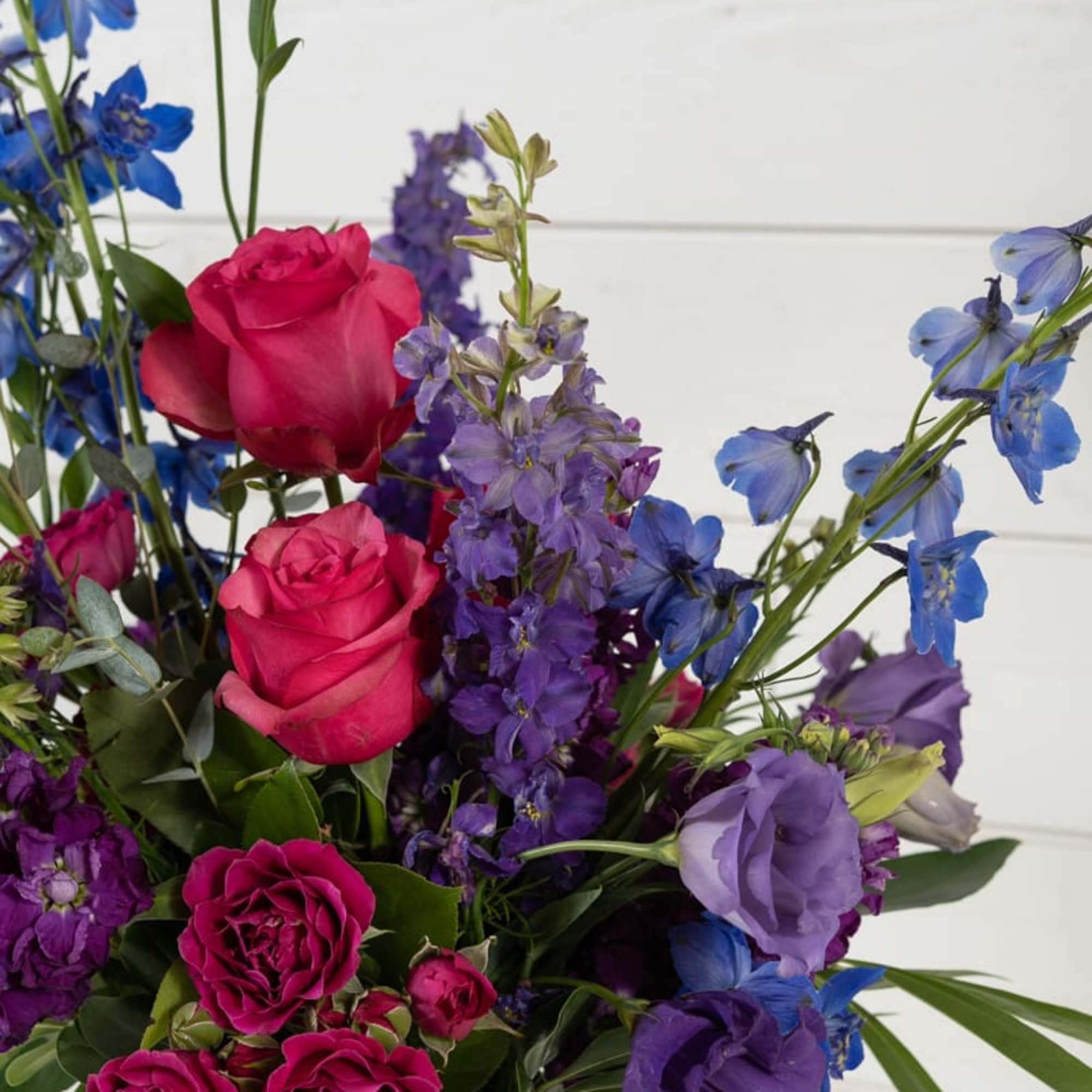 Bouquet of pink roses and purple-blue flowers in a glass vase