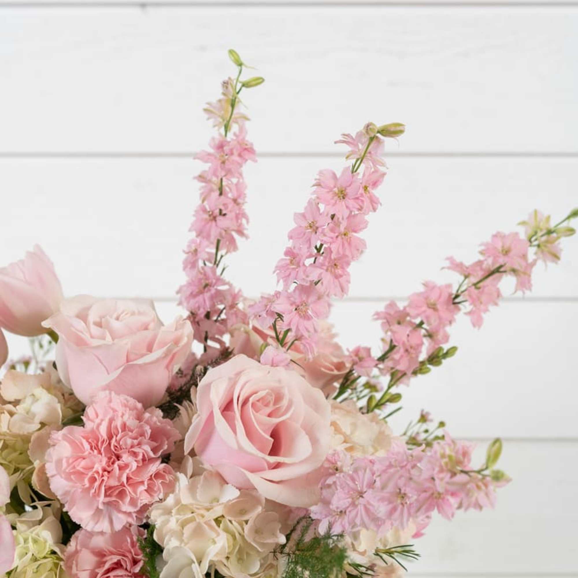 Pink roses and carnations with tall pink blossoms in a glass vase