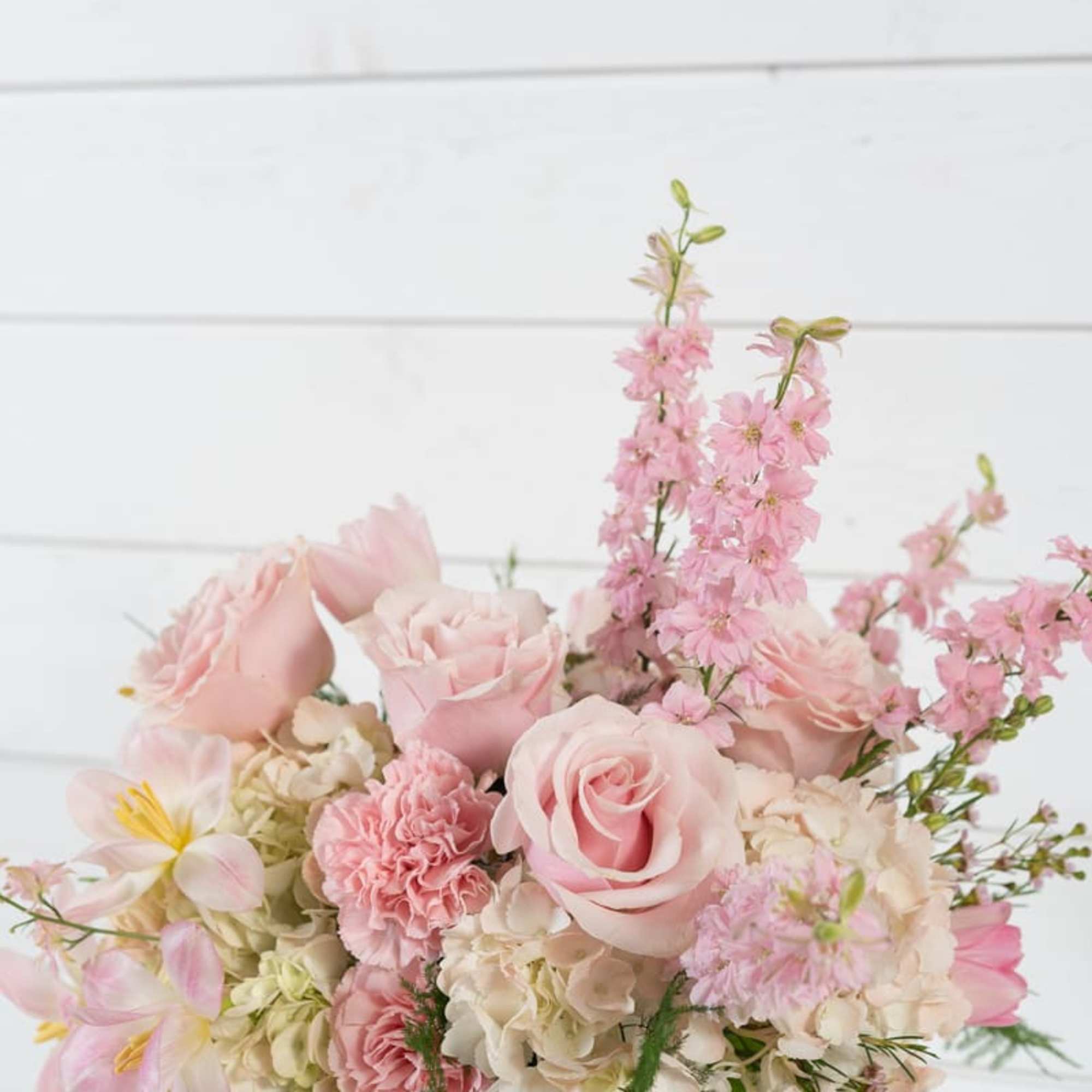 Pink roses and mixed pastel flowers arranged in a glass vase