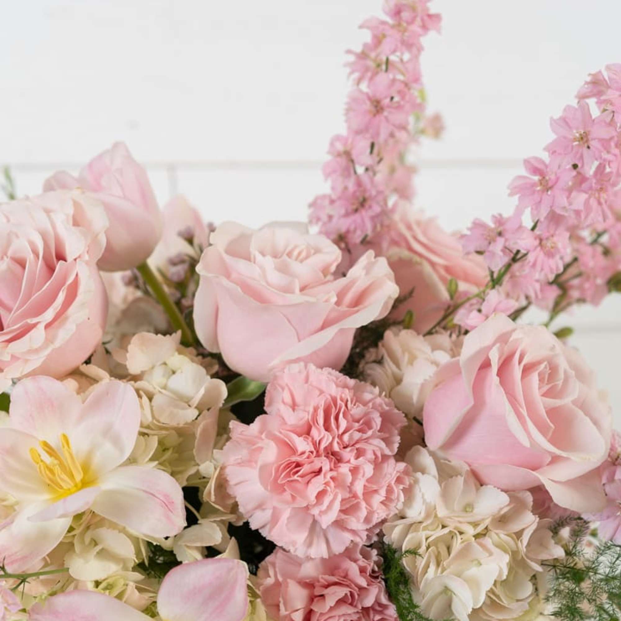 Pink roses and carnations with pale tulips in a glass vase