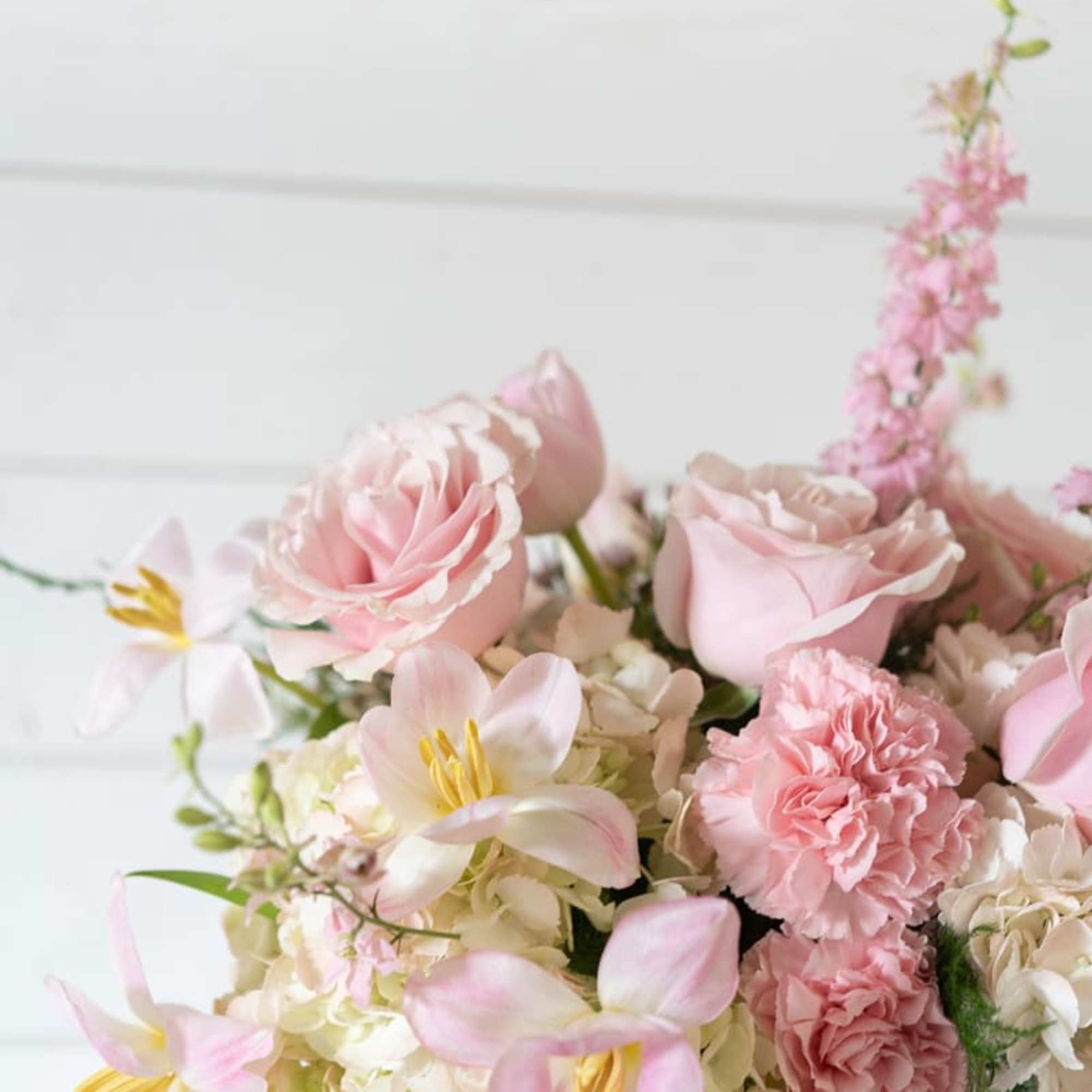 Pink roses and carnations with pale blooms in a glass vase