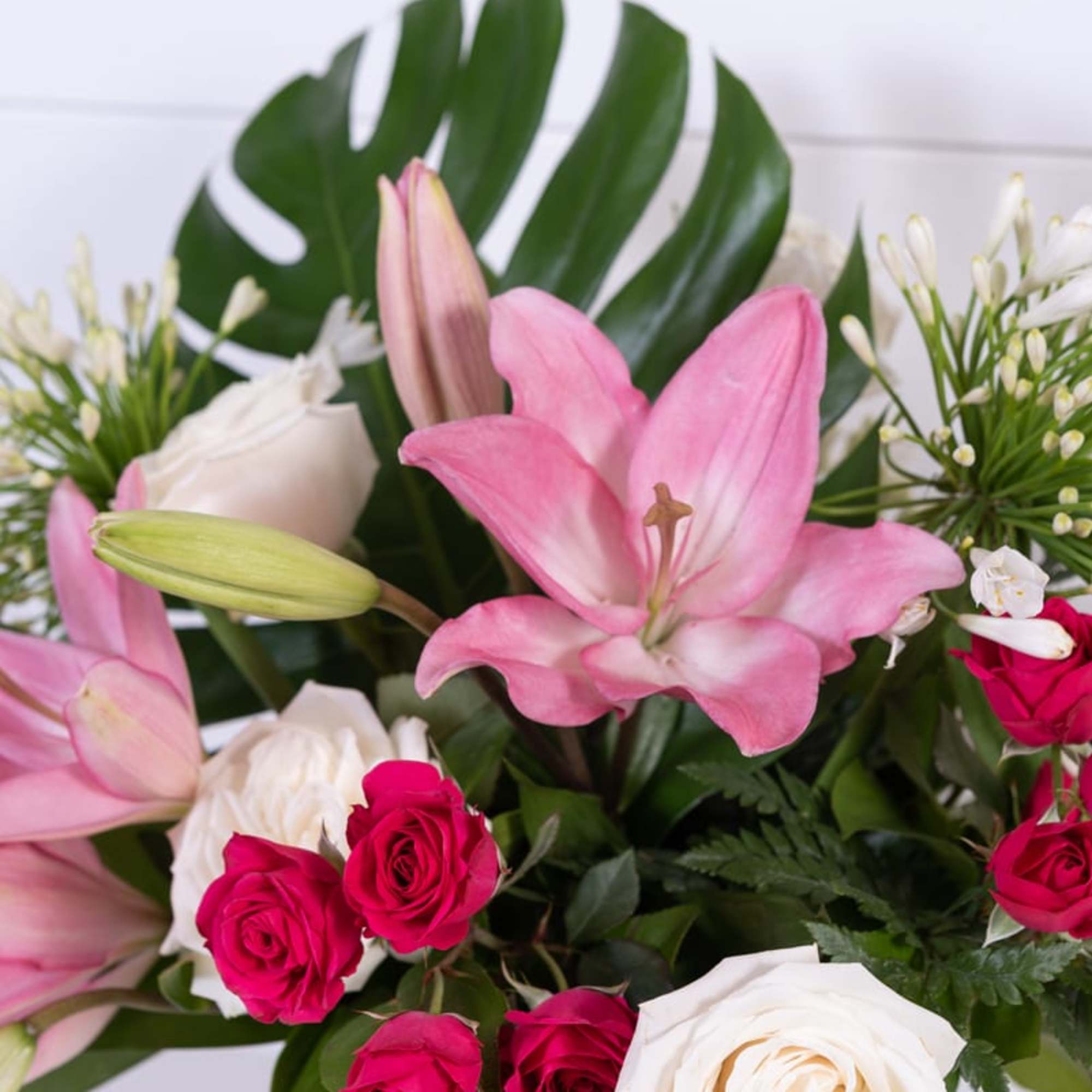 Pink lilies and roses arranged in a clear vase