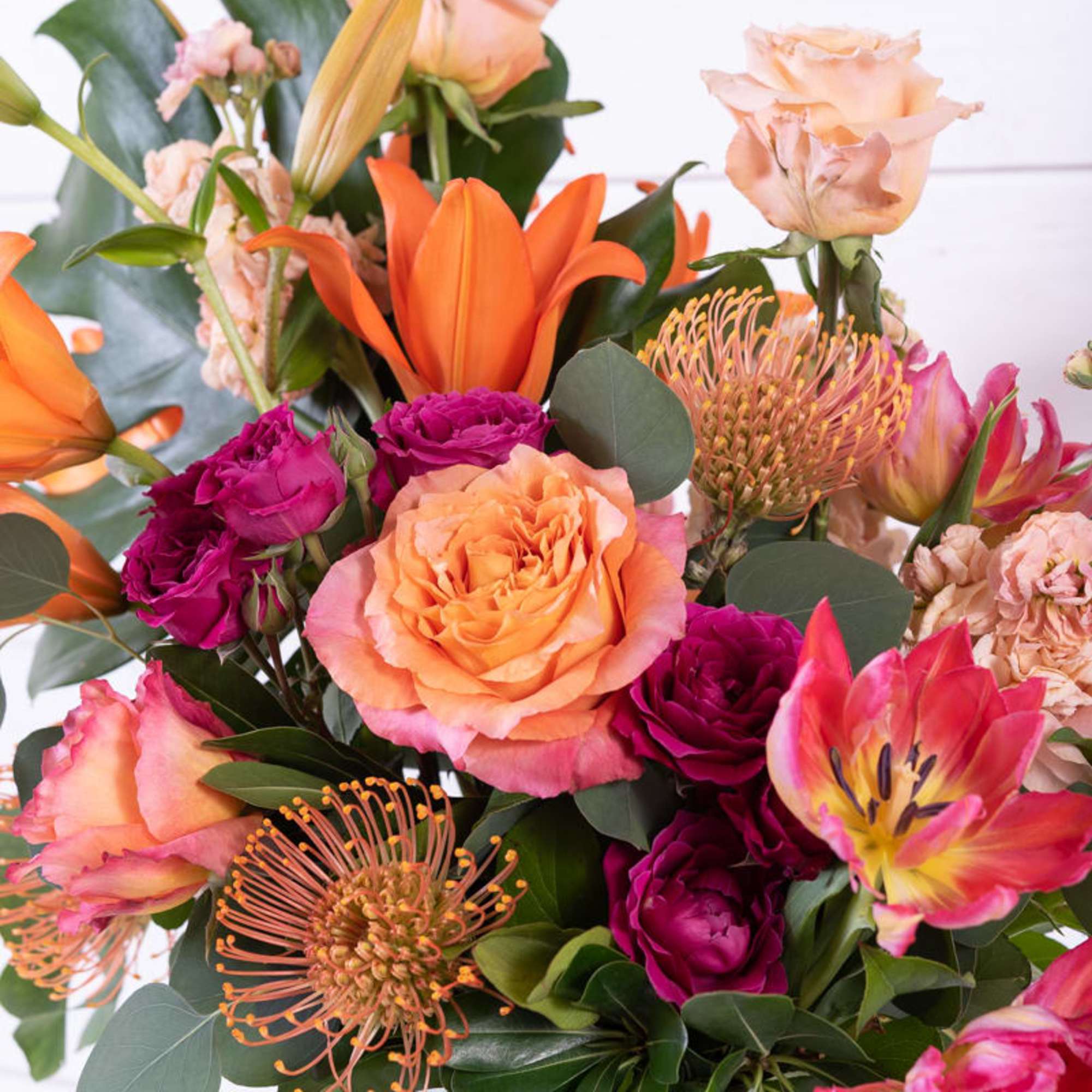 Bouquet of orange, pink, and peach flowers in a glass vase