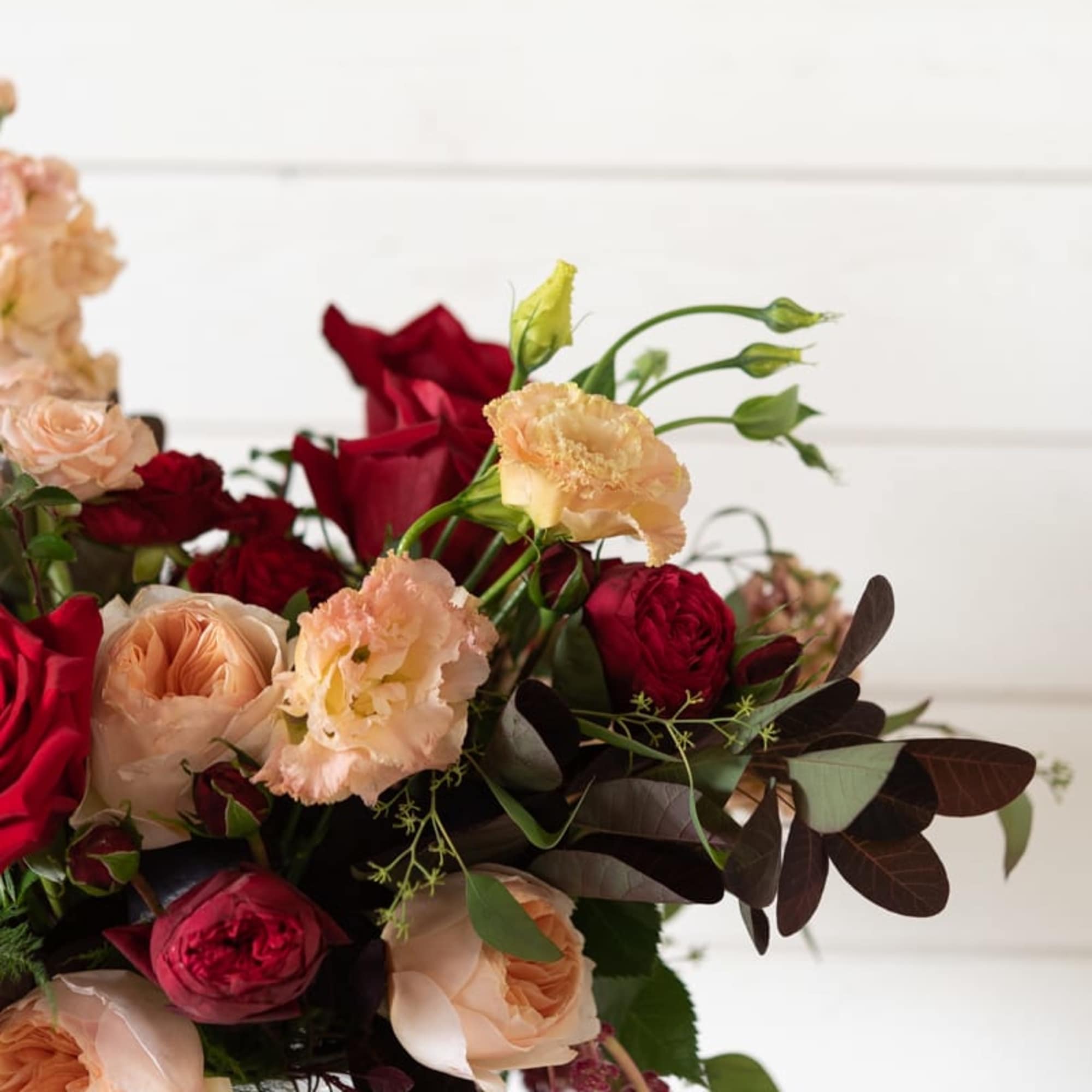 Bouquet of red and blush roses with peach carnations in a glass vase