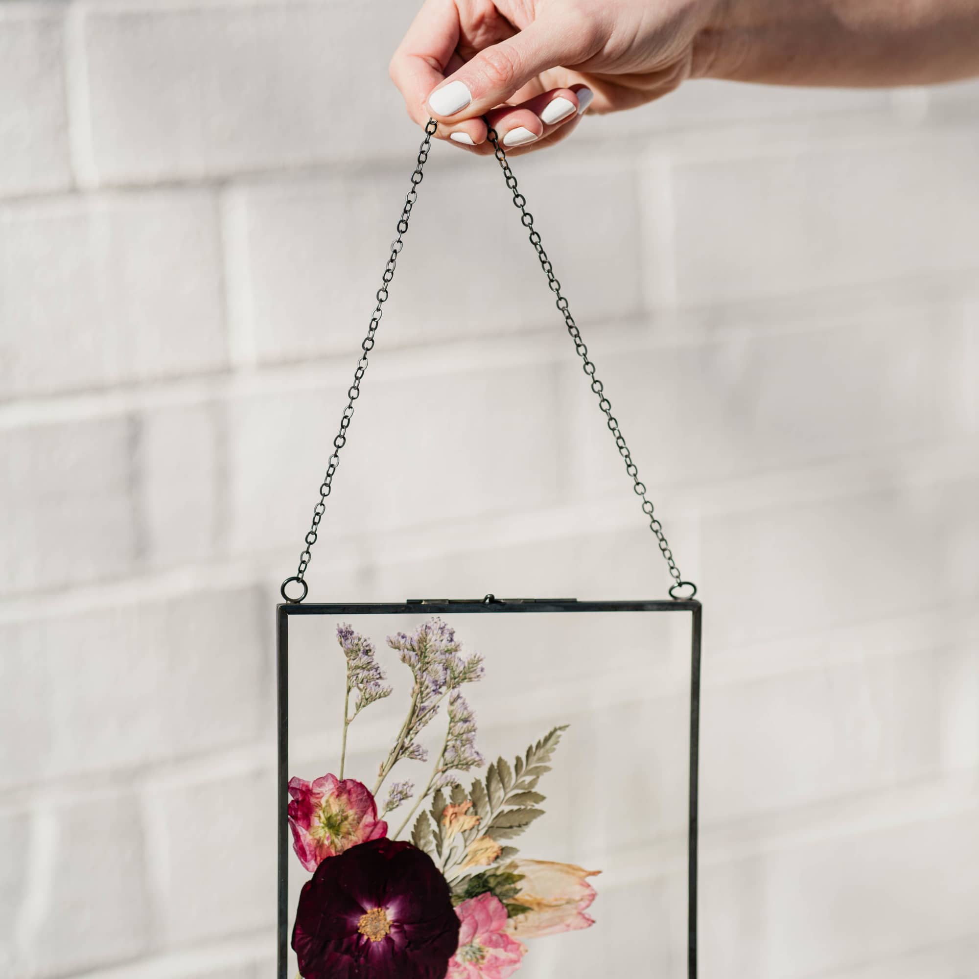 Pressed flowers in a black-framed hanging glass panel