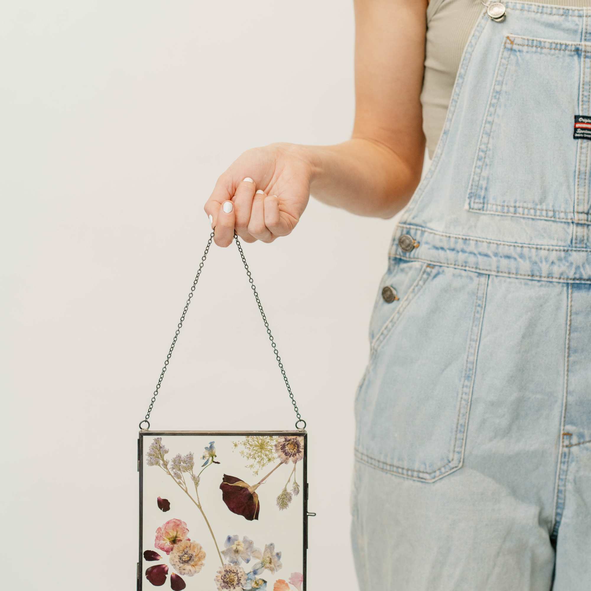 Person holding a framed pressed-flower hanging display
