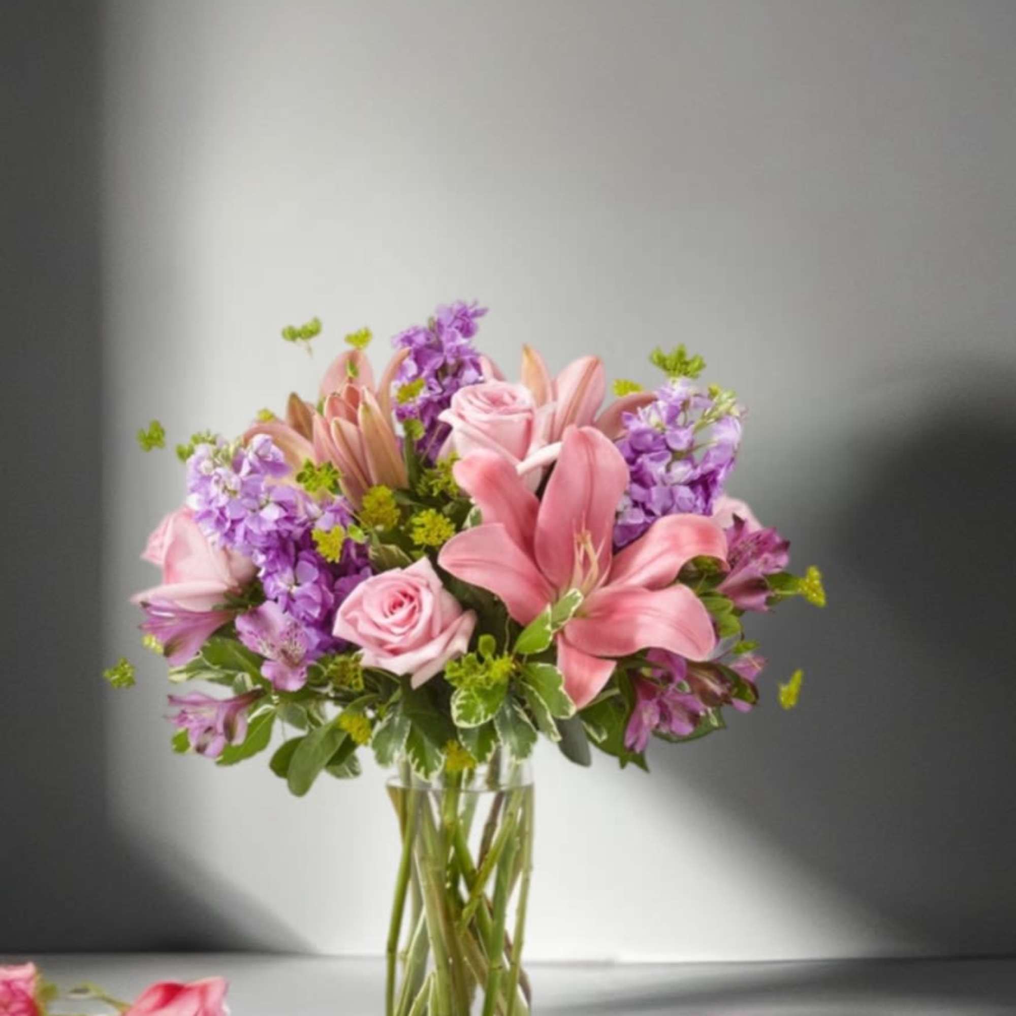 Pink lilies and roses in a clear glass vase