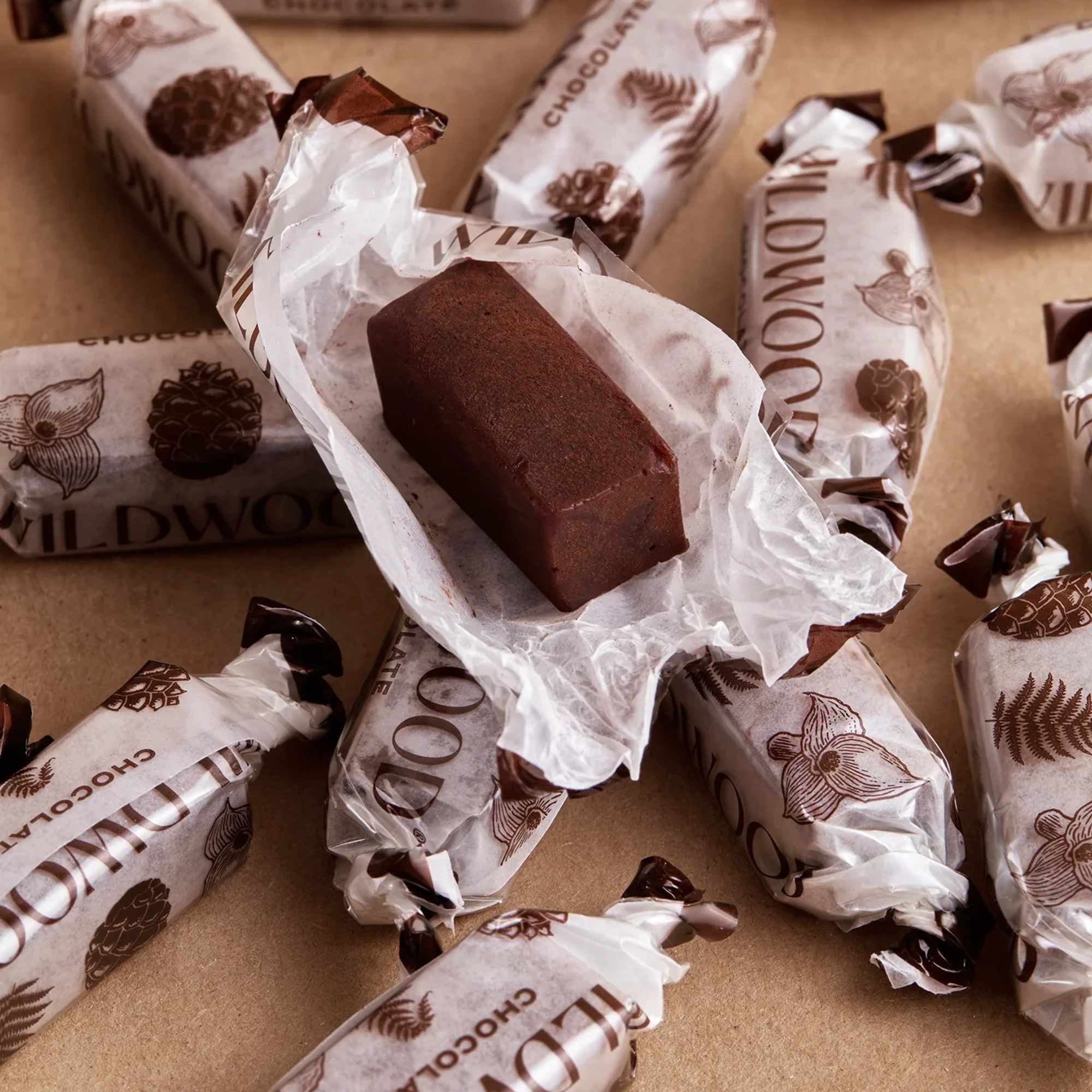 Individually wrapped rectangular chocolates with one unwrapped piece in the center