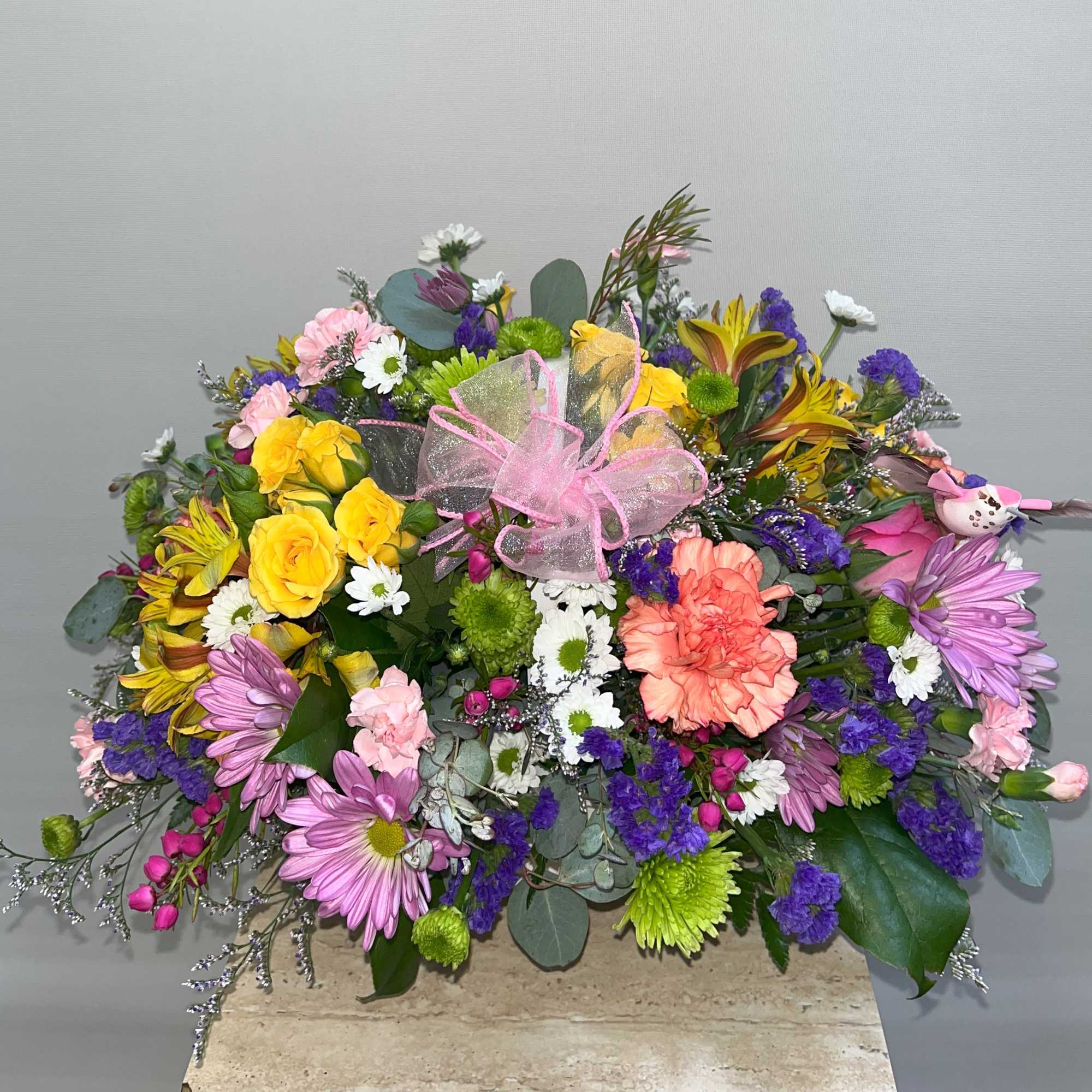 Mixed bouquet with roses, carnations, daisies, and a pink ribbon bow