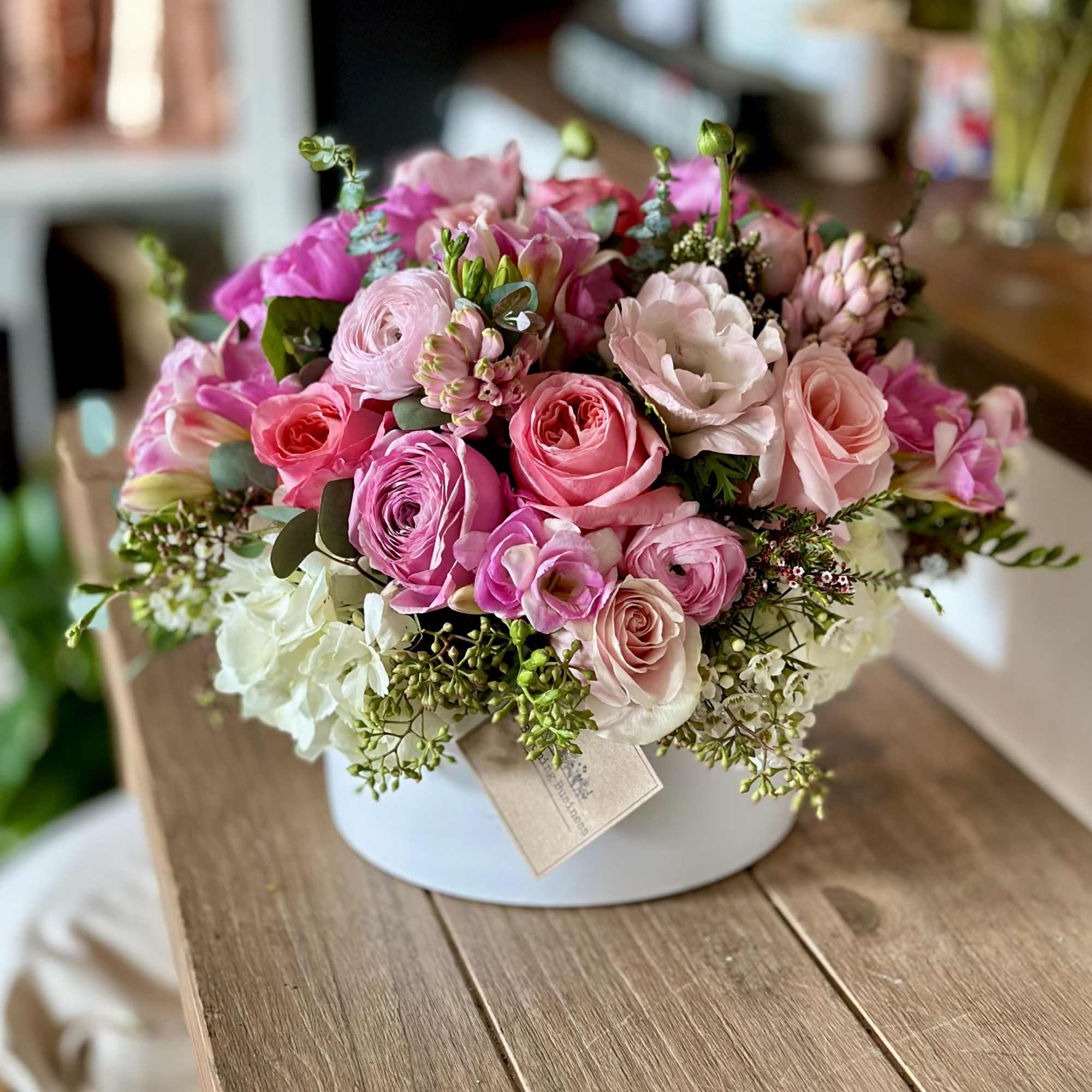 Pink and white mixed flower arrangement in a round box
