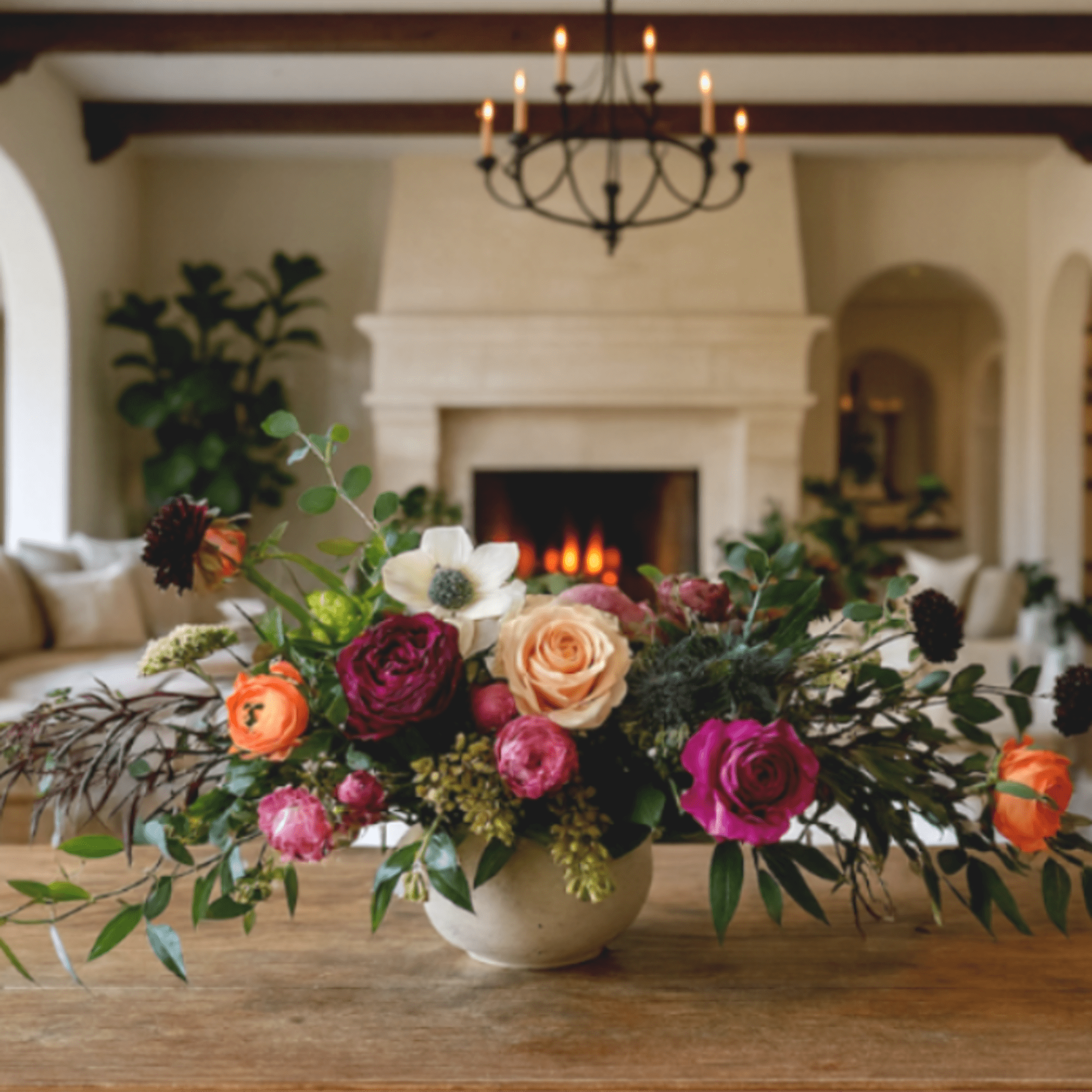 Mixed rose arrangement in a low ceramic vase on a wooden table