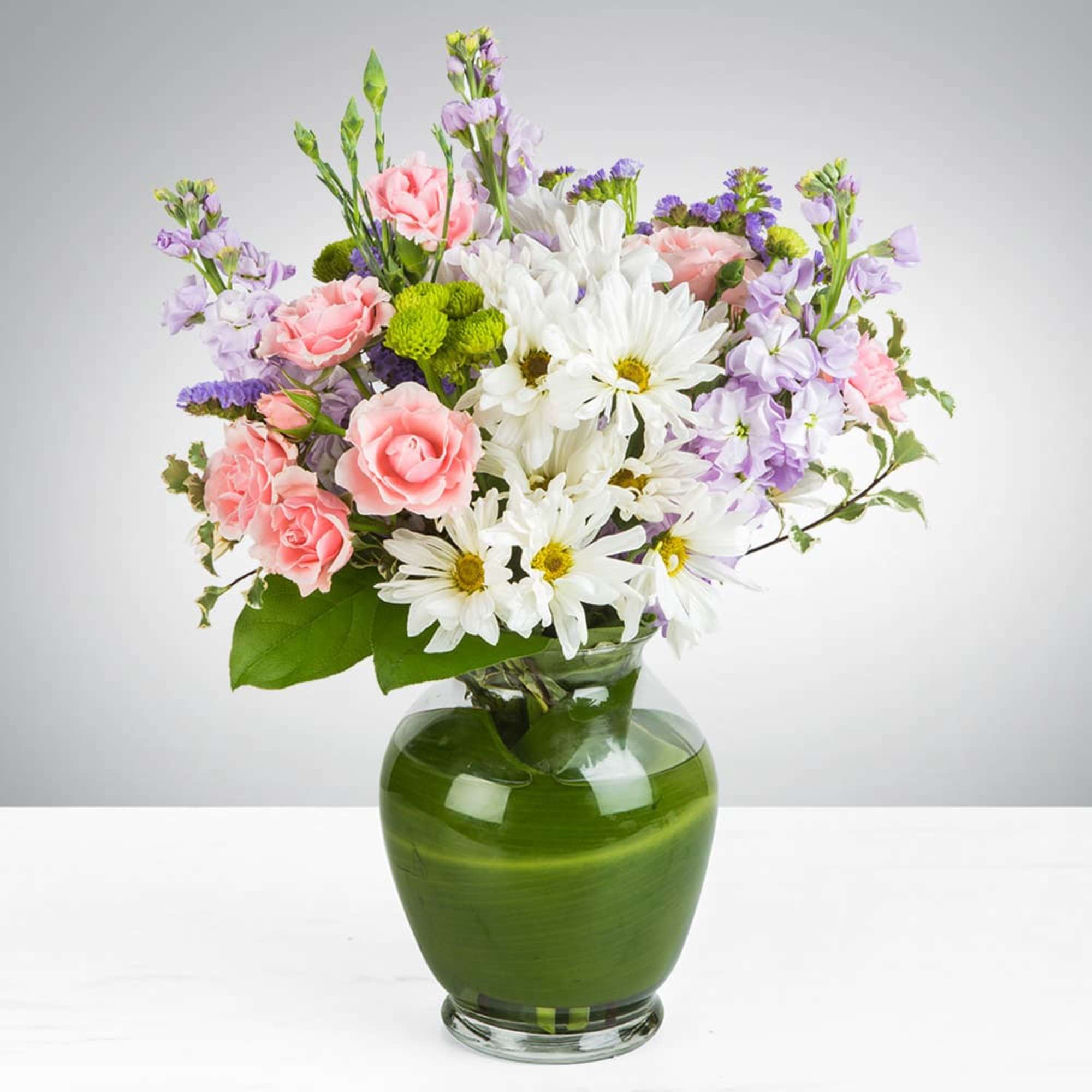 Pink and white flowers arranged in a green glass vase