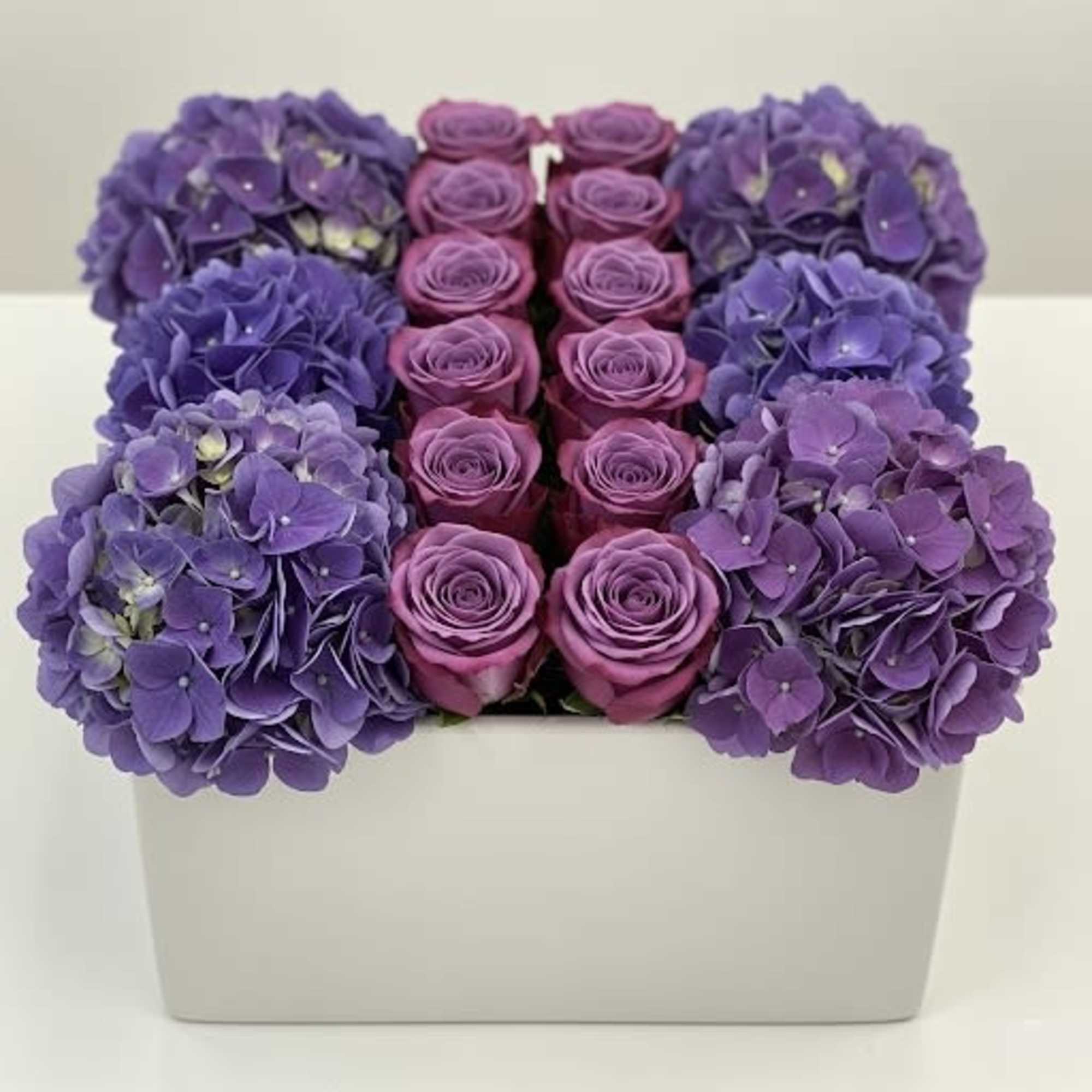 Purple hydrangeas and pink roses arranged in a white box